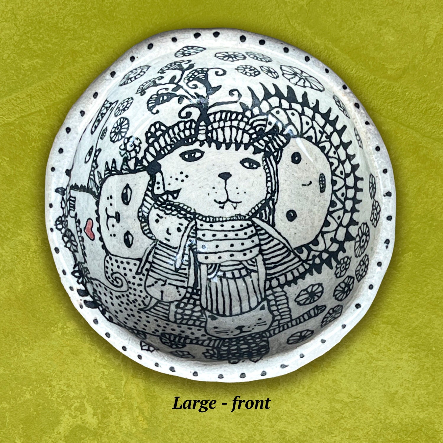 Circular bowl with a stylized bear wearing a hat and scarf. Black and white with a small red heart.