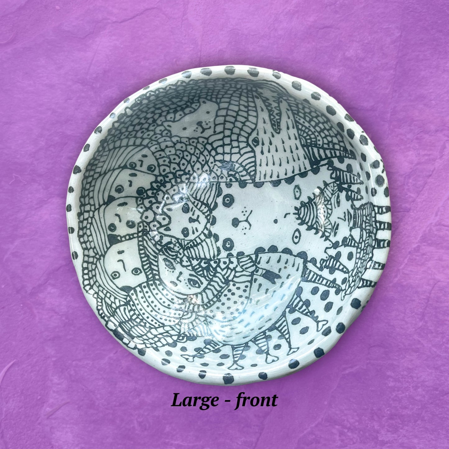 Ceramic bowl with black and white patterns shown set on a purple background.