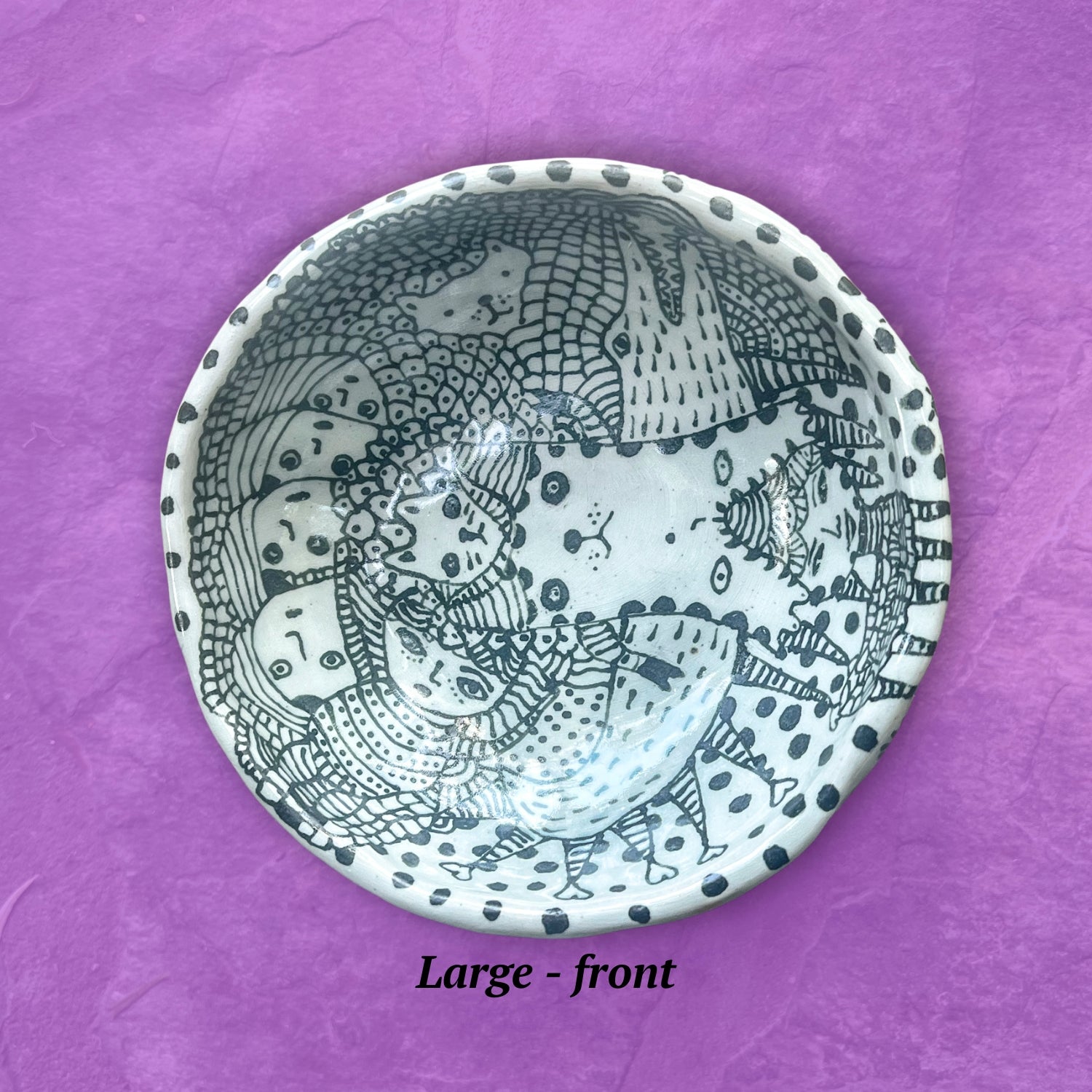 Ceramic bowl with black and white patterns shown set on a purple background.