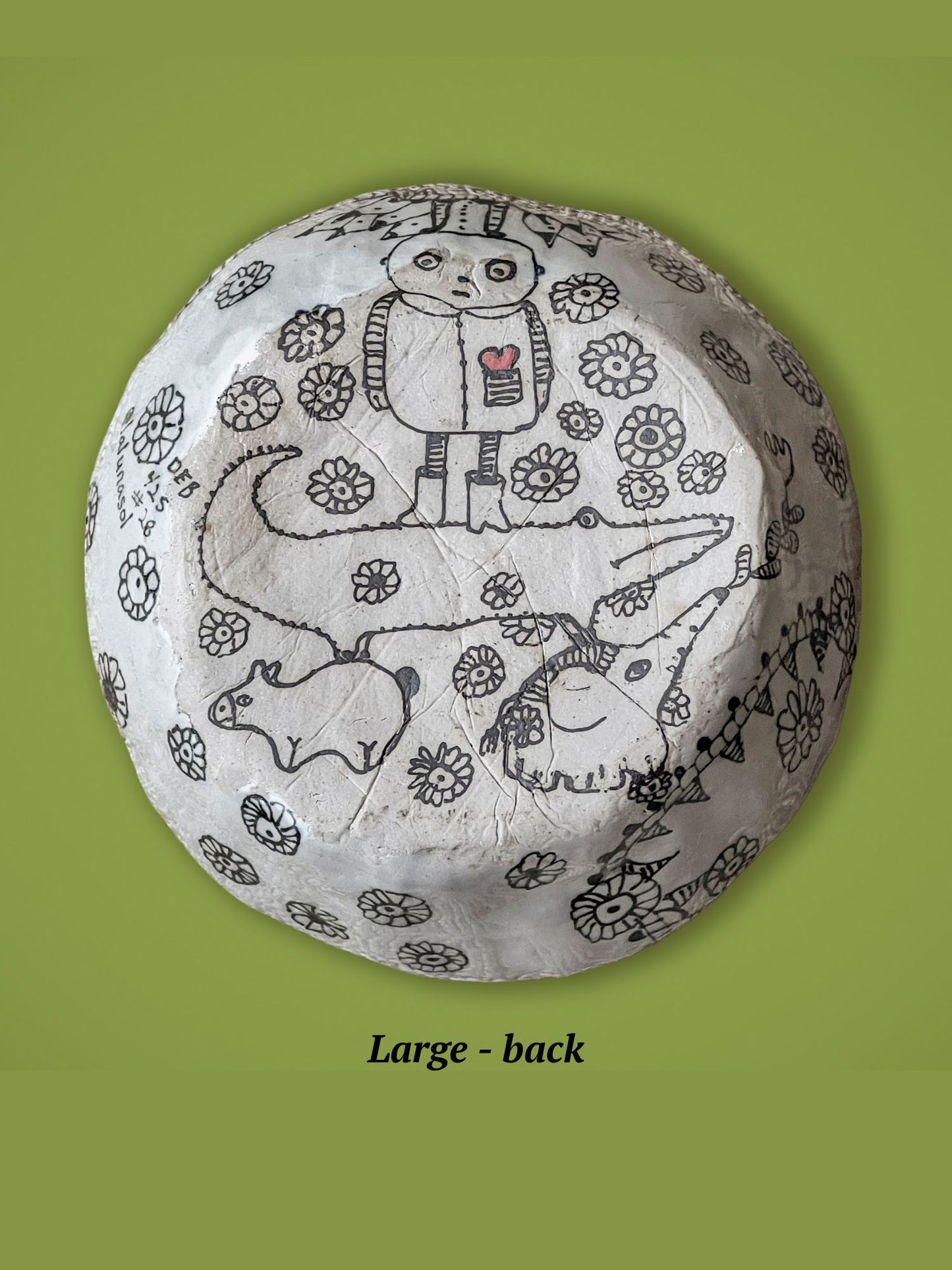 Round ceramic bowl with animal drawings on a green background. This is the backside of the previous bowl. It has a small man standing on a crocodile. The surface is matte, not glossy.