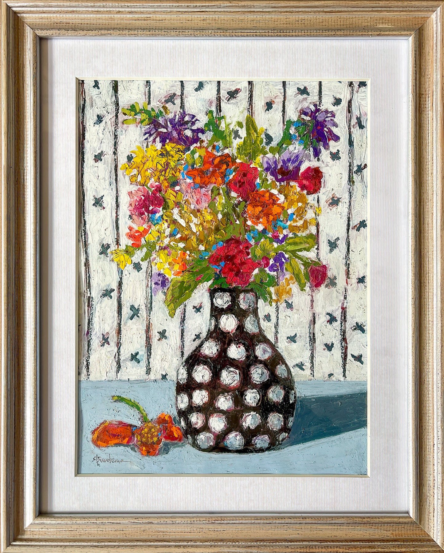 This piece is framed with a textured off white mat in a light wooden frame.