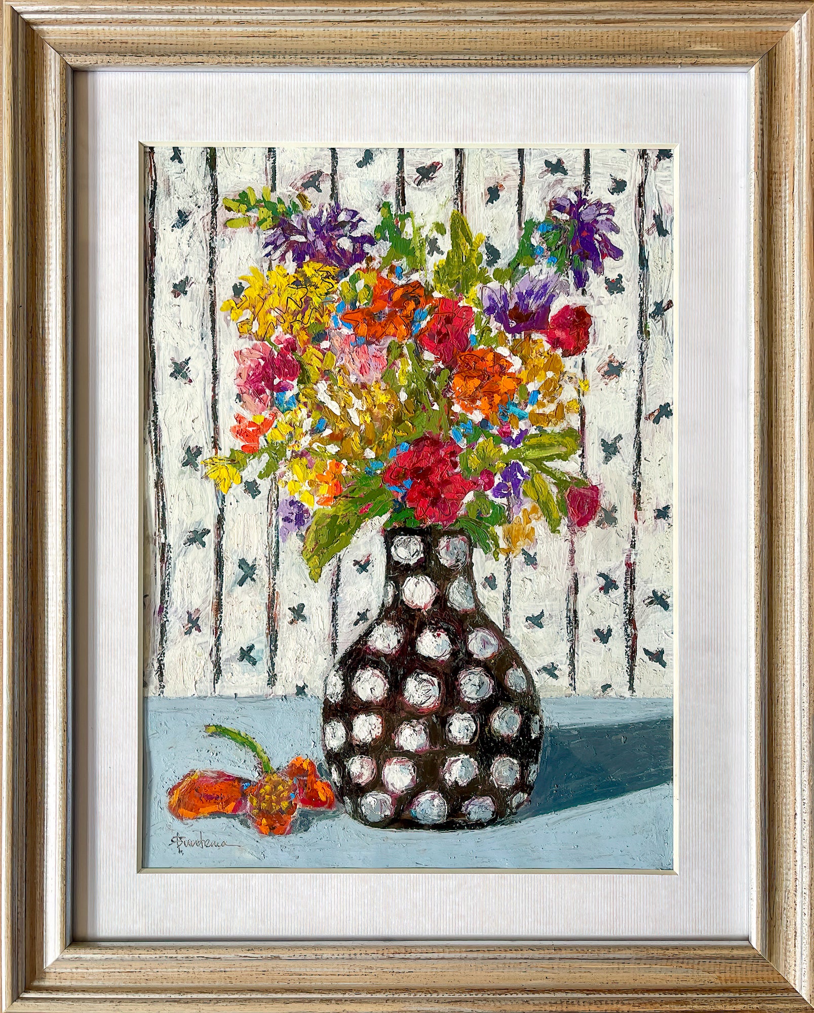 This piece is framed with a textured off white mat in a light wooden frame.