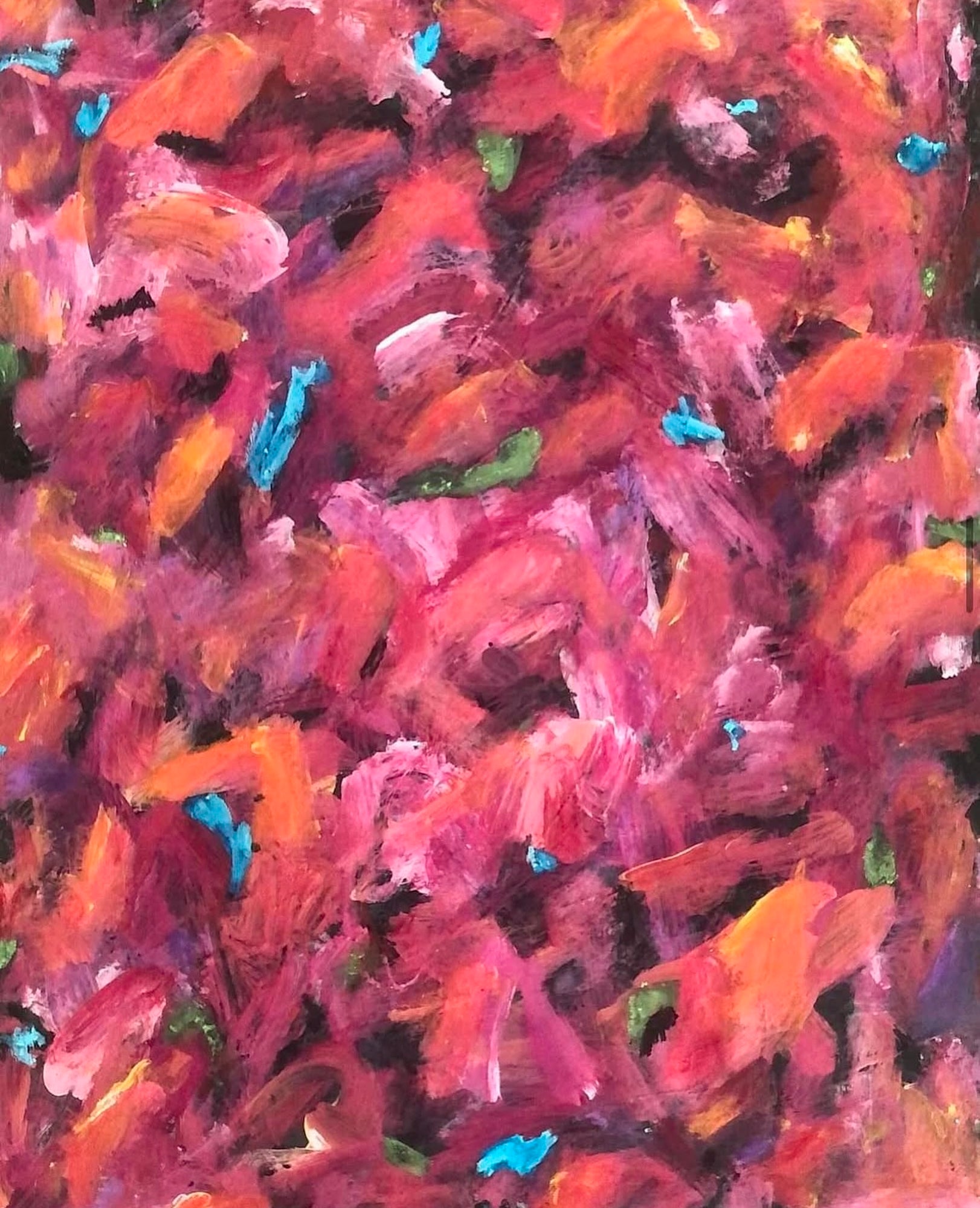 This image shows a close up of the flowers highlighting the various shades of reds, pinks and oranges that form the flowers. Small drops of blue and green also show.