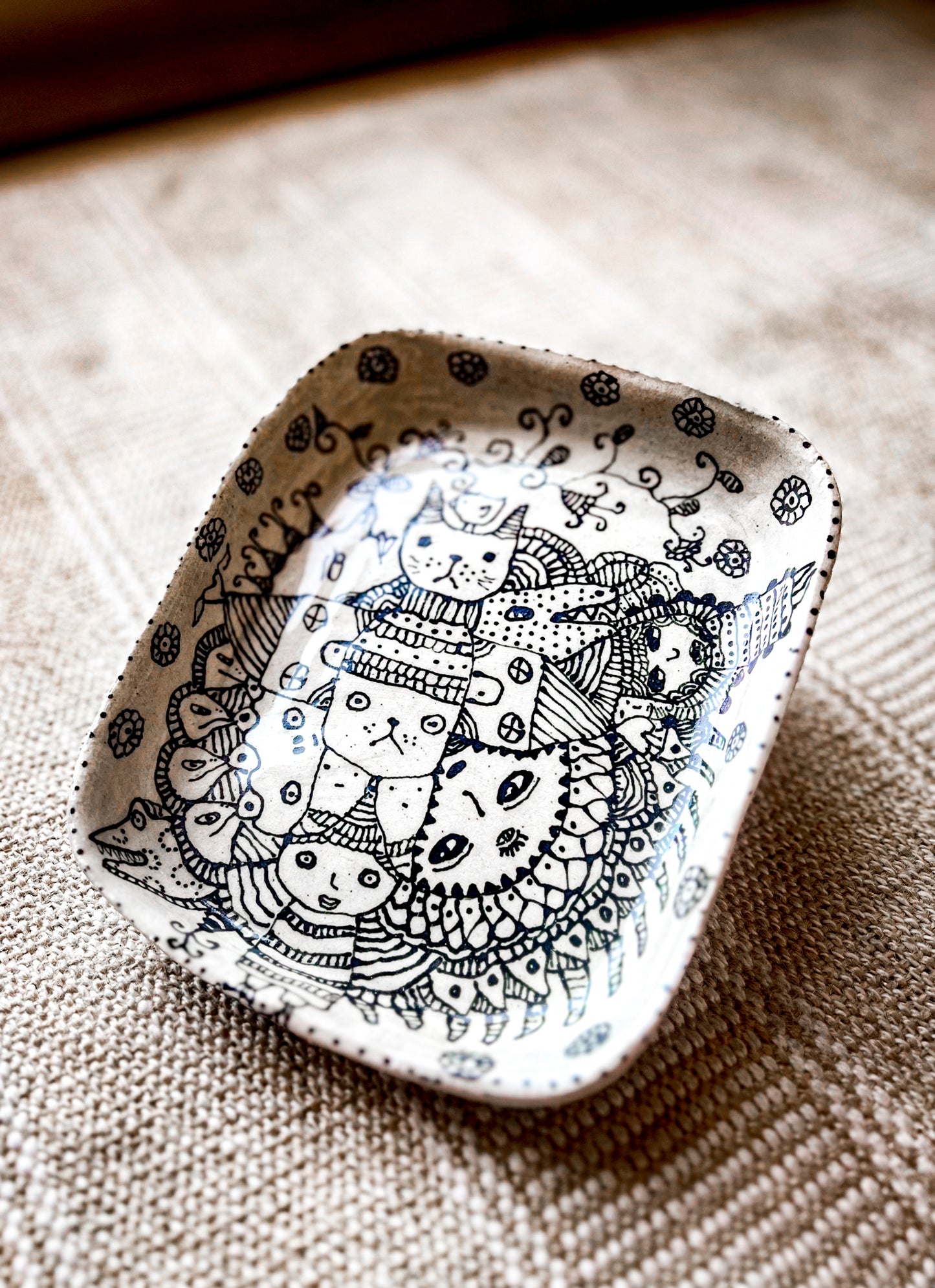 Decorative ceramic dish with black line art design on a textured surface to show the dimensions of the plate.