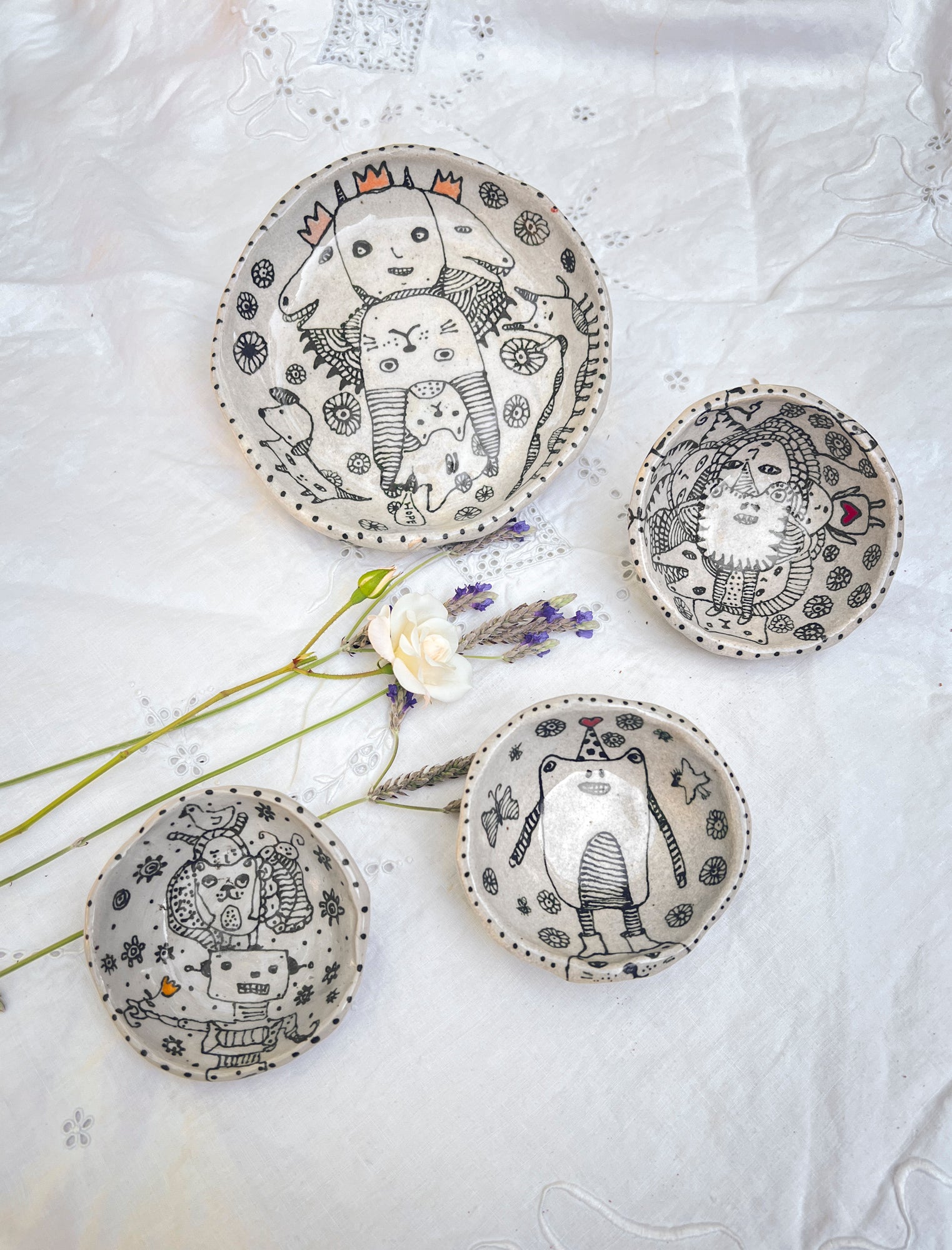 Set of hand-drawn original ceramics with black graphic artistic designs on a neutral gray clay background