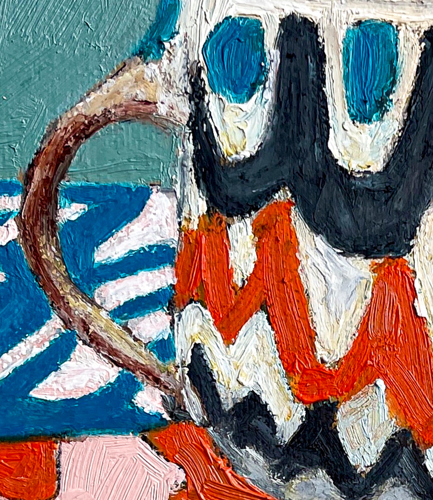 This close up image shows the scalloped design of the mug with white, red and black curved lines. Teal blue dots line the top of the mug. We also see the background wall of teal and what might be a blue napkin with a white design.