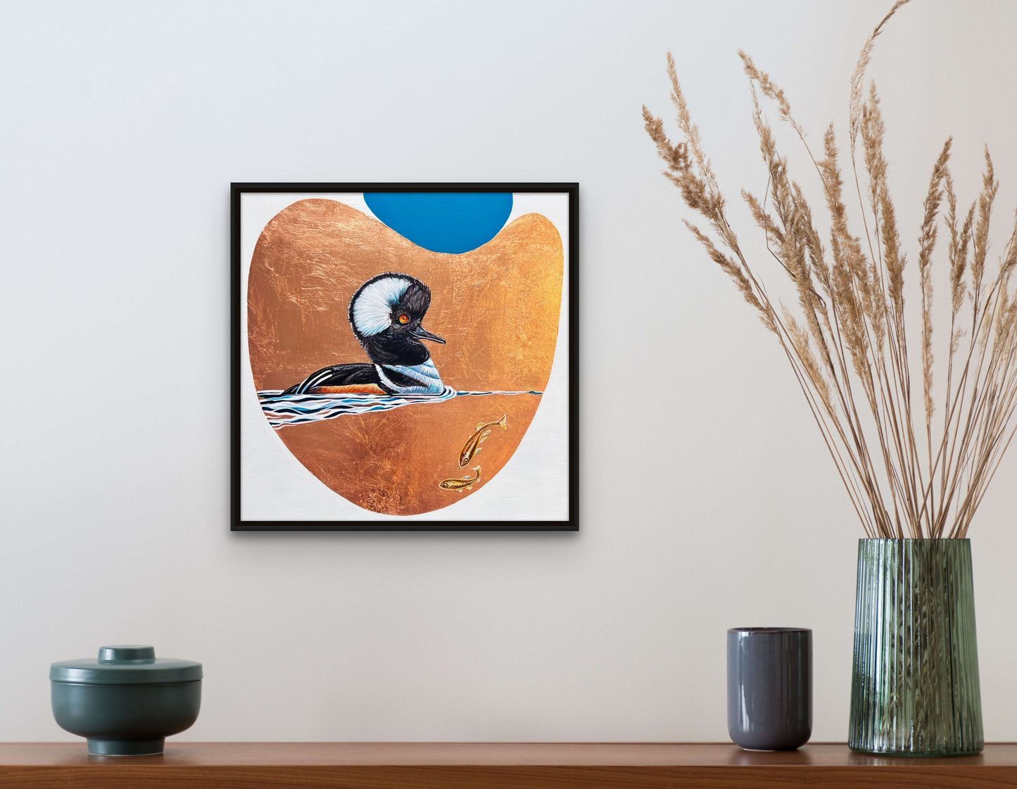 Framed waterfowl on a copper leaf background with blue sky accent. Two small fish swim nearby in situ; artist Marie Lavallee; 12"x12"