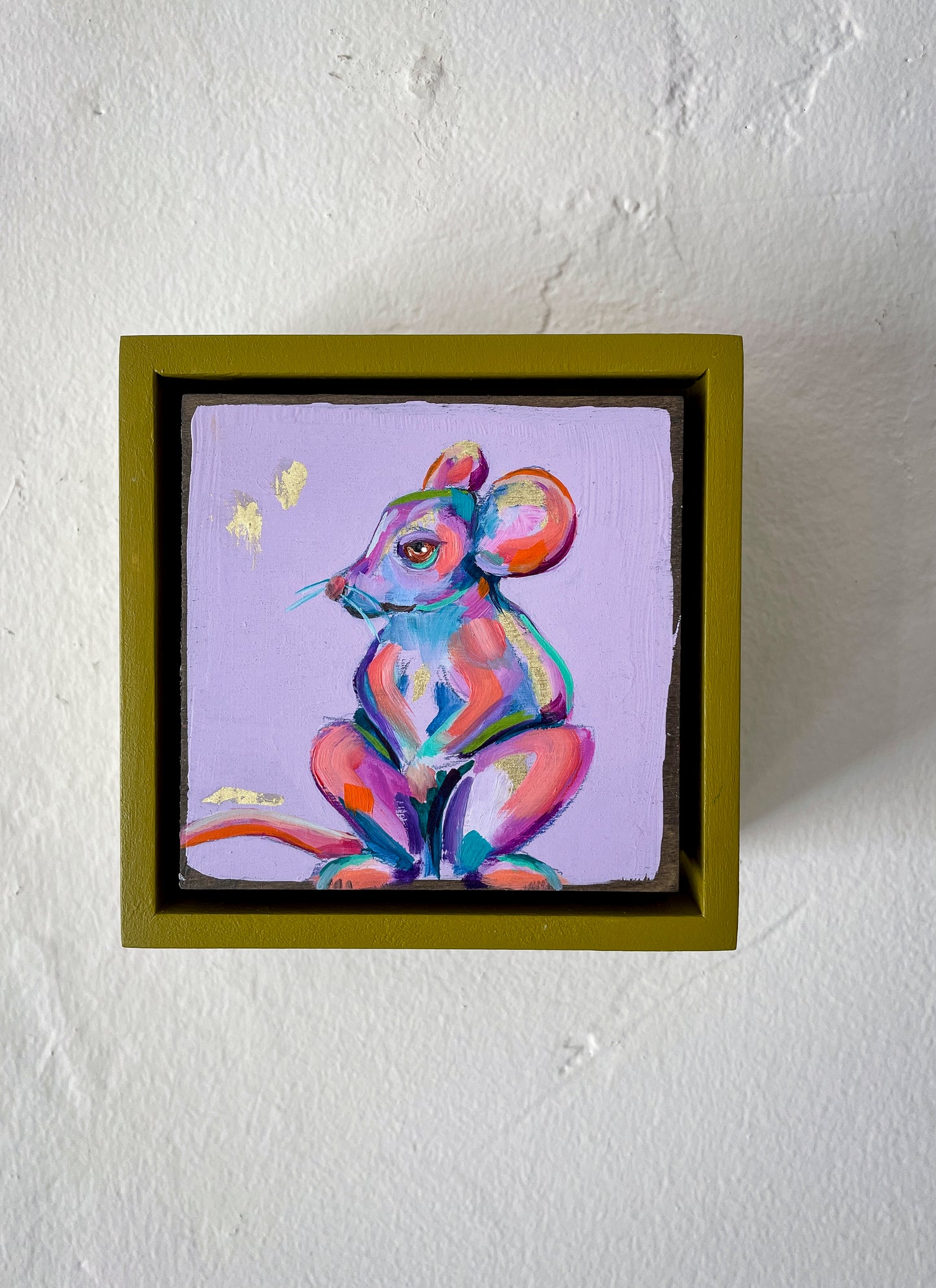 Colorful whimsical painting of a mouse in blues, purples, pinks with touch of gold leaf; 5"x5" incl painted frame; artist Shaney Watters; shown on wall in situ