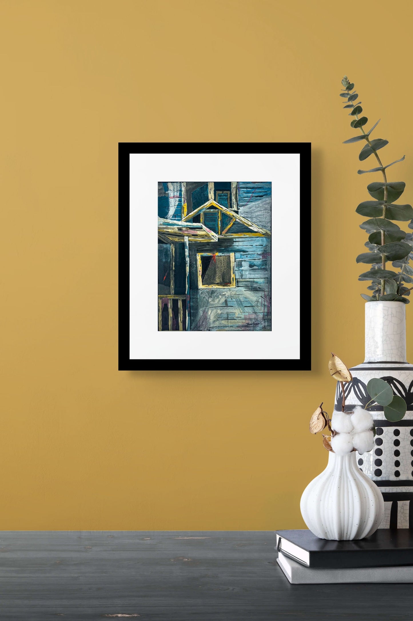 Abstract painting using suggestions of a structure, window, wood boards, railing; palette of blues with yellow highlights; artist Bob Hogue; framed w/white mat and black wood; shown in situ on a mustard yellow wall with vases and plants on table nearby