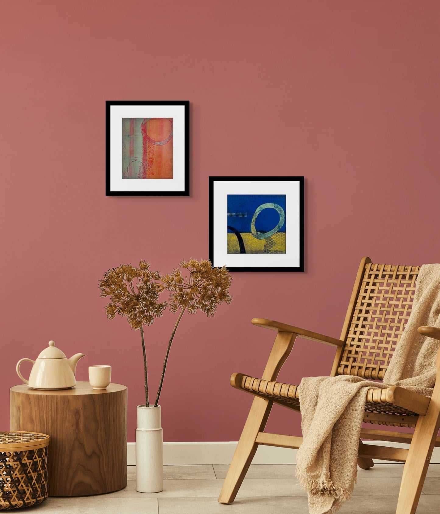 Abstract art piece with blue and yellow background and black textured elements; frame of white mat and black wood; artist Bob Hogue; shown in situ with companion piece 'Art Echo' on rose color wall w/chair, table, and tea set