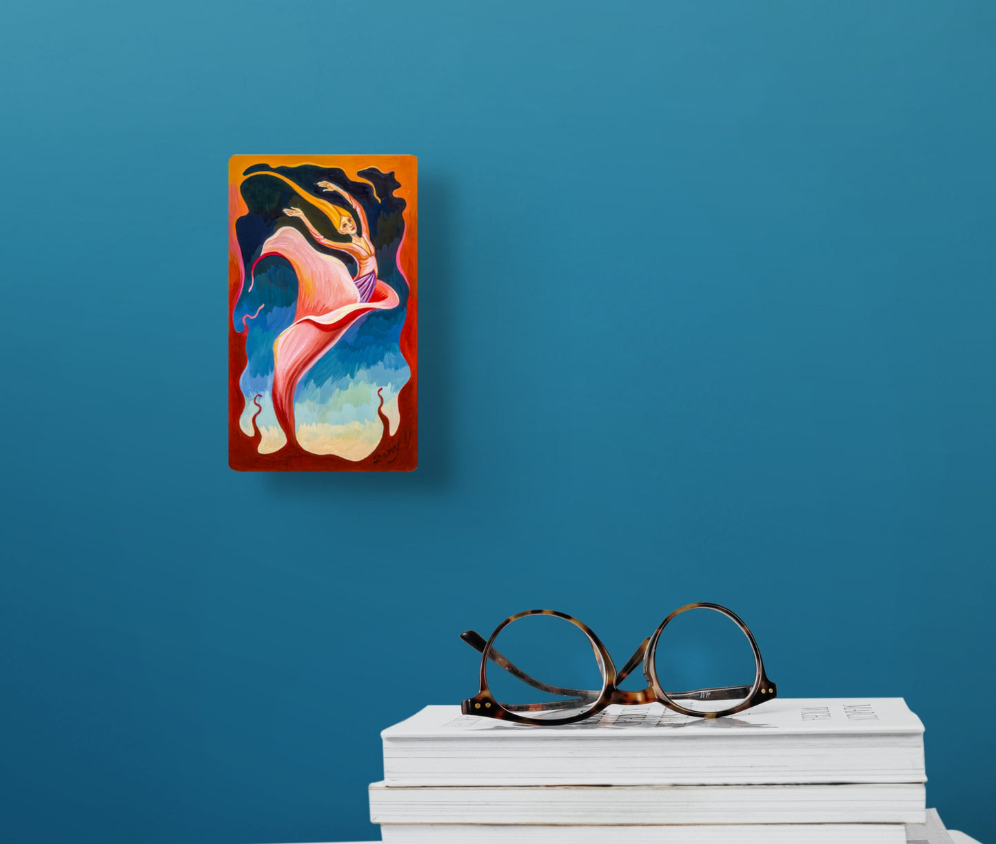 Bloom III hands aon a bright blue wall next to a stack of books with a pair of glasses sitting on them.