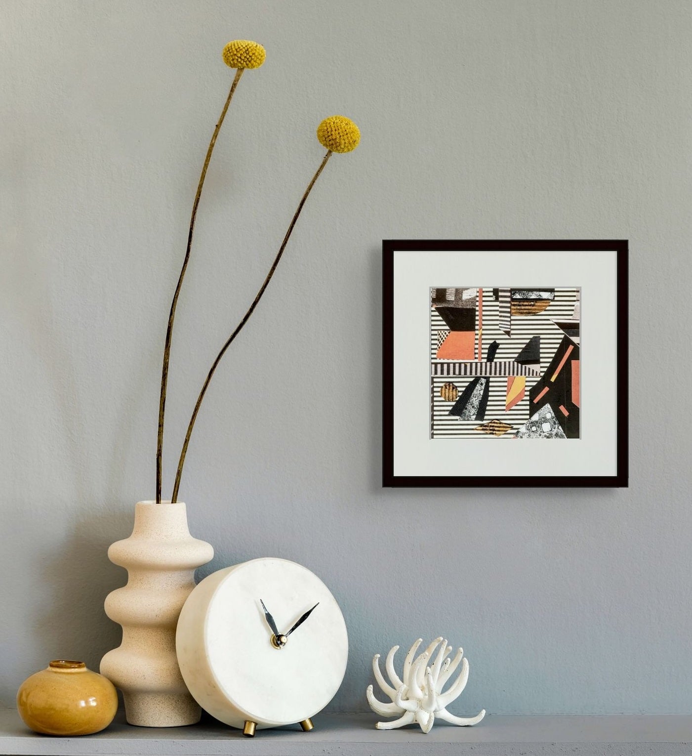 Decorative items including a vase with yellow flowers, a clock, and 'Going Straight' framed in a black wooden frame are shown against a gray wall.