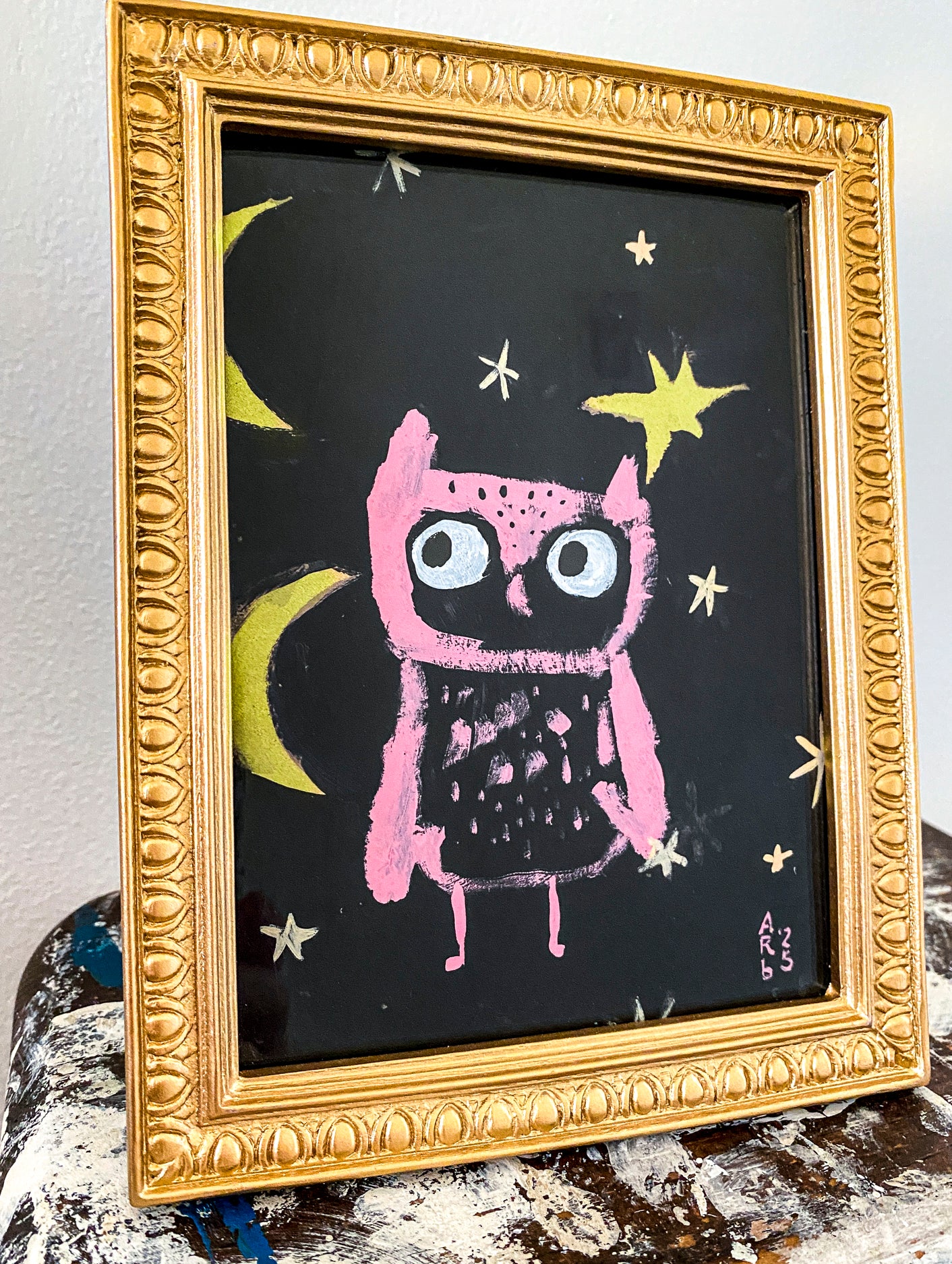 Pink Owl & Two Moons is show here in its frame from the side. The frame is gold and ornate.