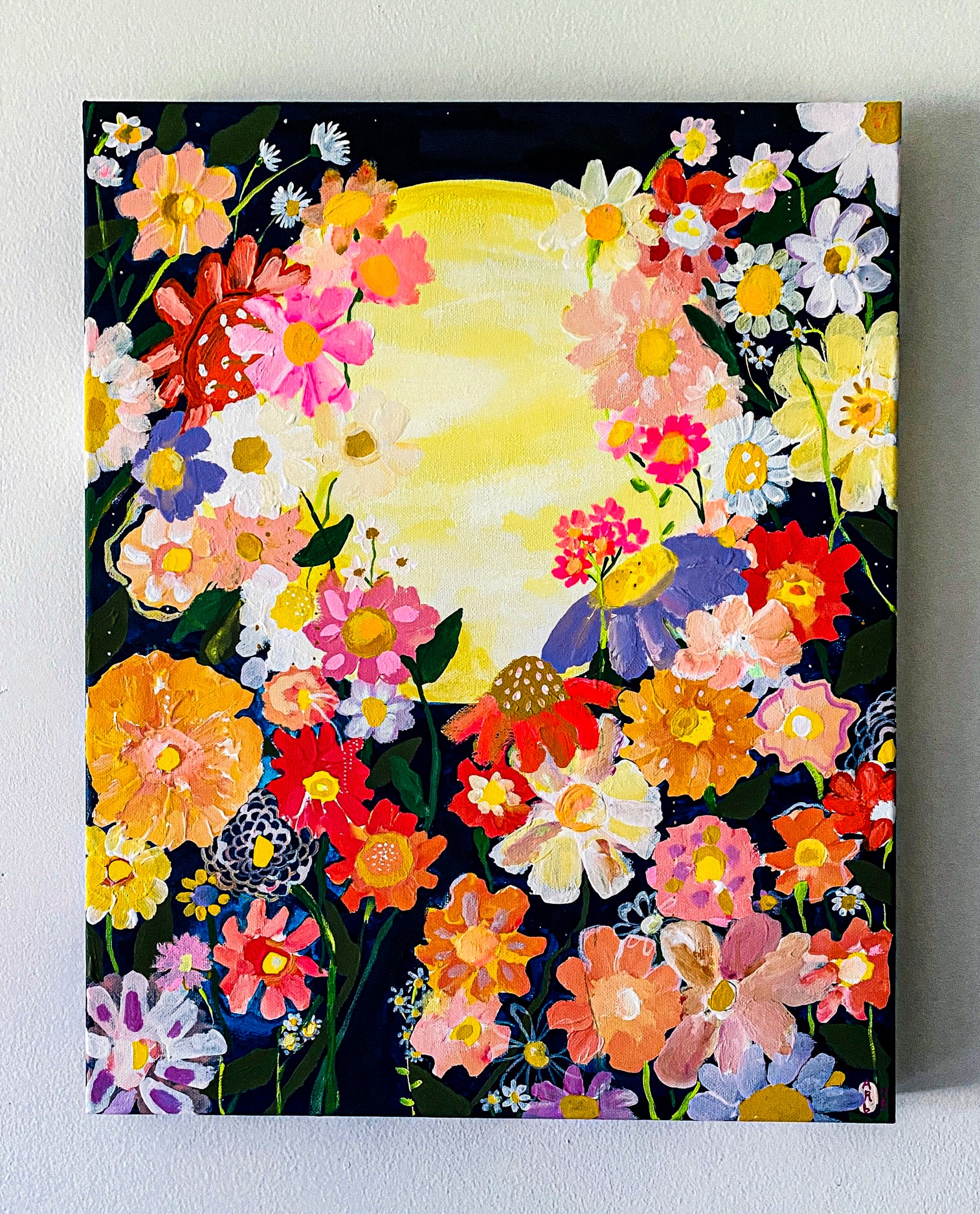April's canvas print of colorful flowers bordering a yellow full moon is set on a dark background. The painting can be hung without a frame as shown here.