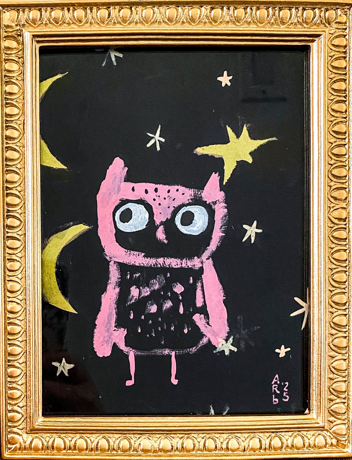 Framed artwork of Pink Owl & Two Moons shown sitting on a tabletop. The frame is gold and ornate.
