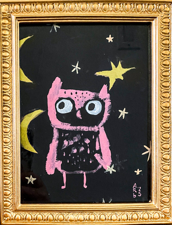 Framed artwork of Pink Owl & Two Moons shown sitting on a tabletop. The frame is gold and ornate.
