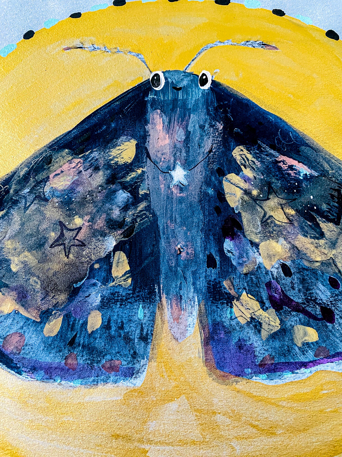 A close up view of the details of the moth against the backdrop of a yellow moon. There is a star in the center of the moth's body.