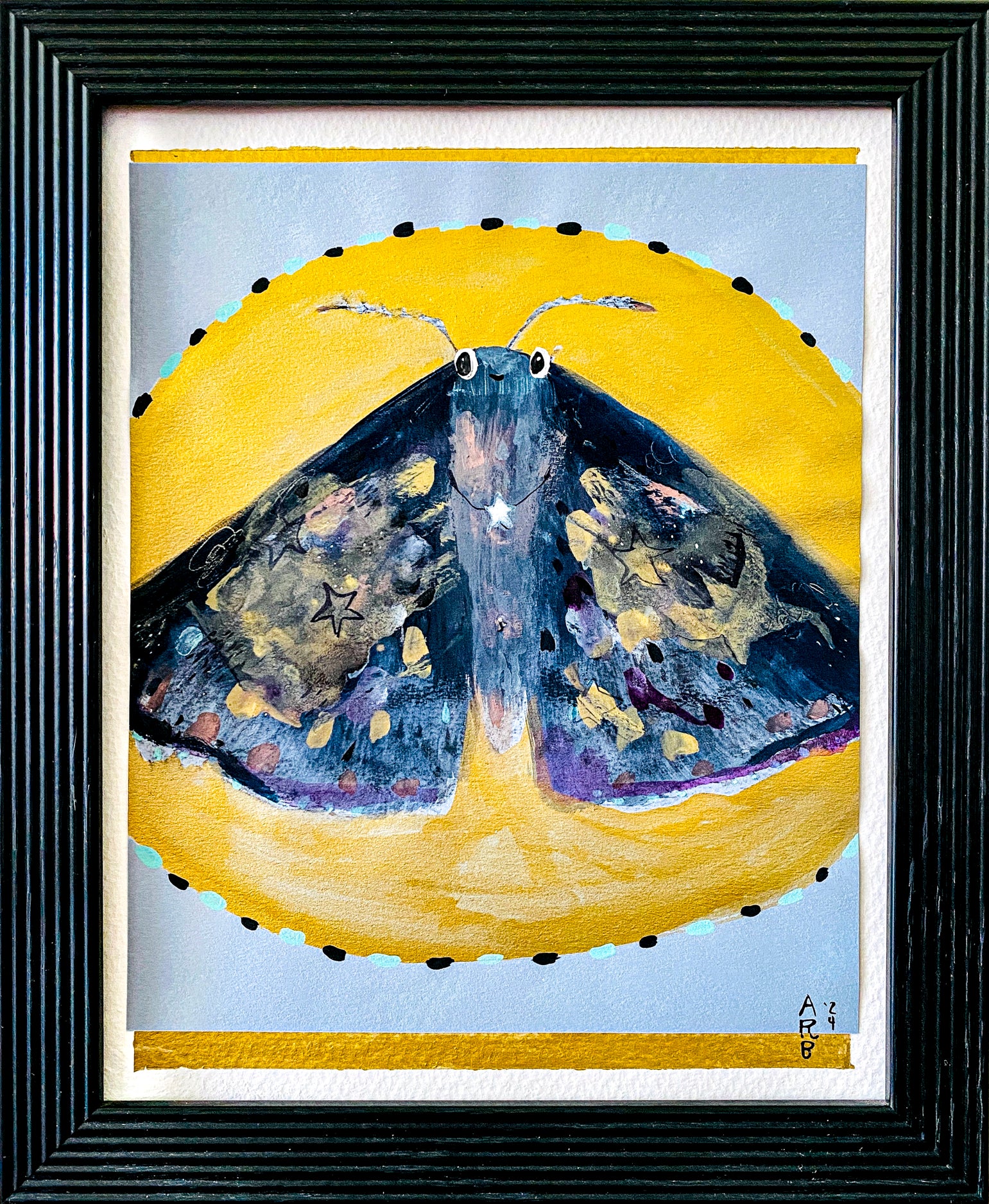 Framed artwork of a beautiful moth against the backdrop of a yellow moon on a light blue background.