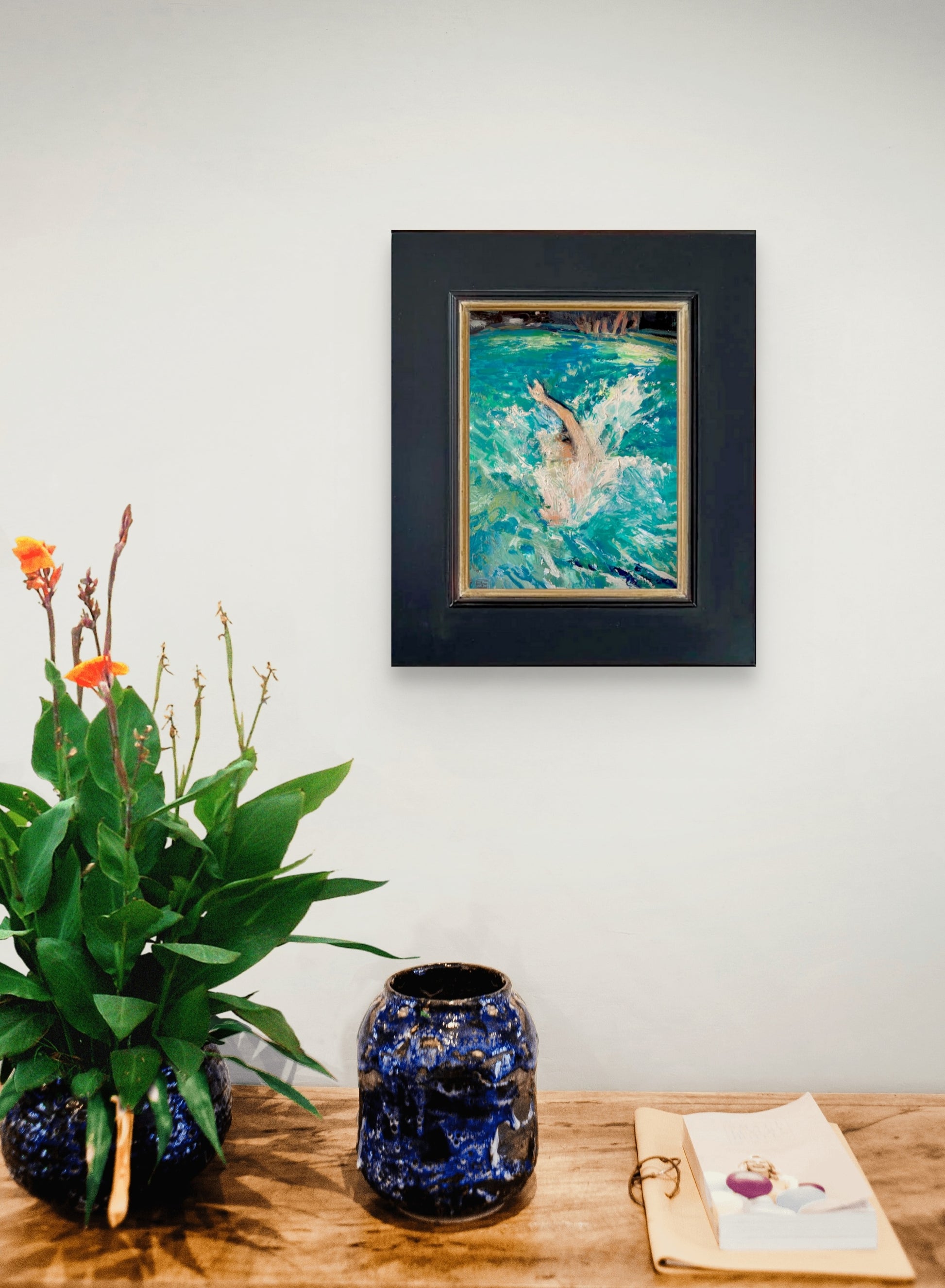 Framed image of Jump on a white wall above a wooden surface with decorative items.