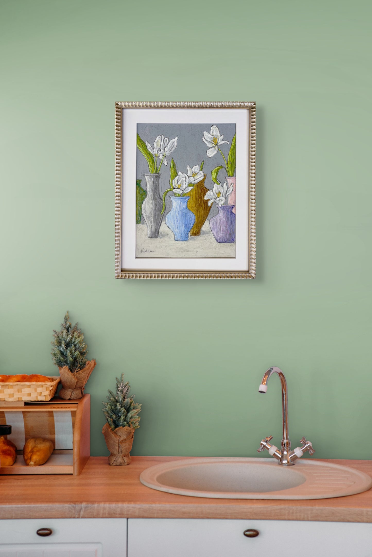Framed image of Let's Pretend hanging on a mint green wall over a sink and counter with decorative items.