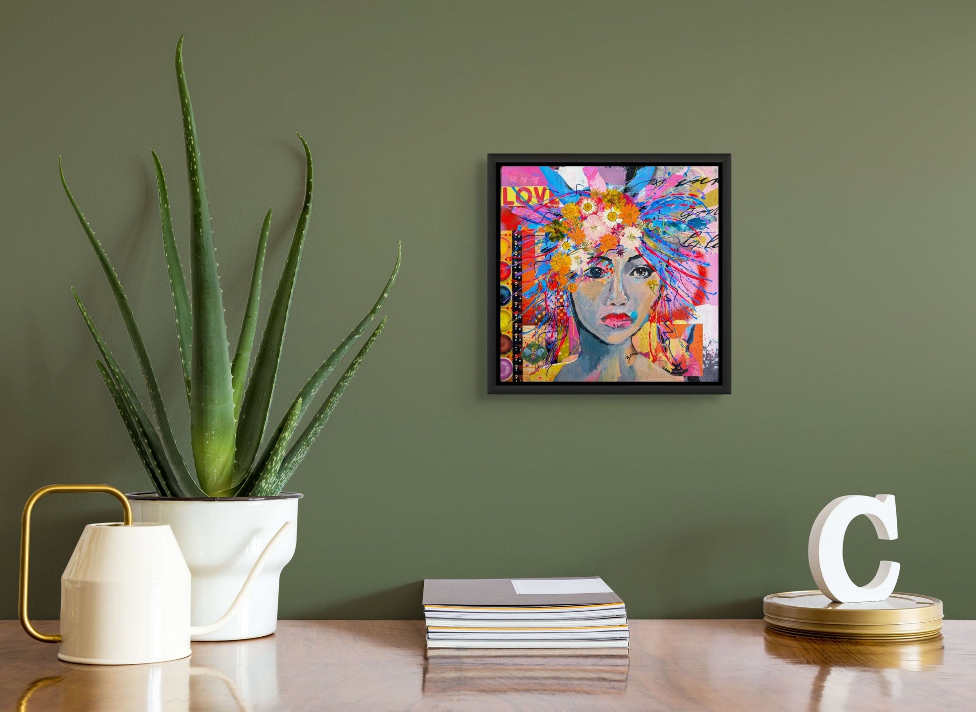 Love is in the Hair has been framed in a black floater frame (not included) and hangs on a green wall above a desk with decor items.
