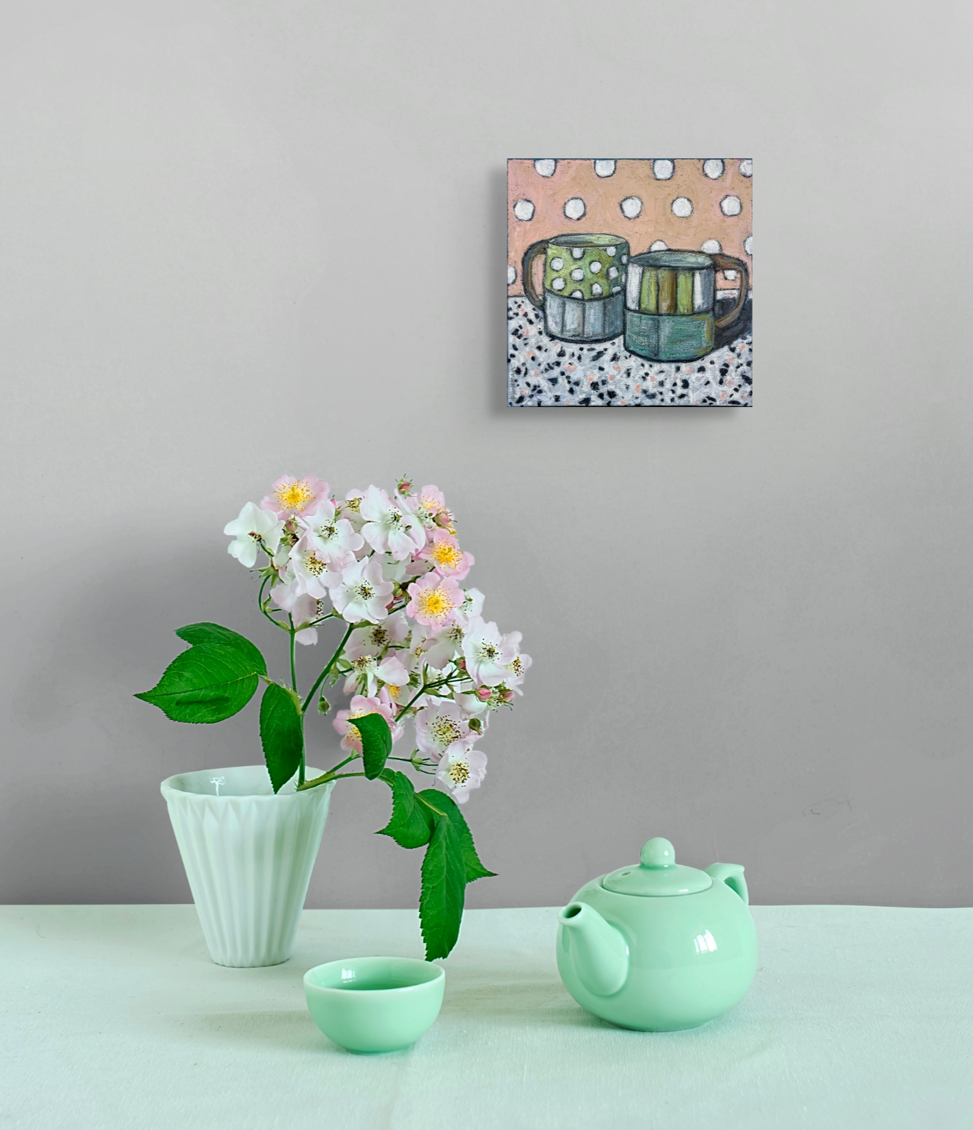 In situ image of the painting hanging over a tea set sitting on a table. There is also a vase of flowers and the colors are coordinated.