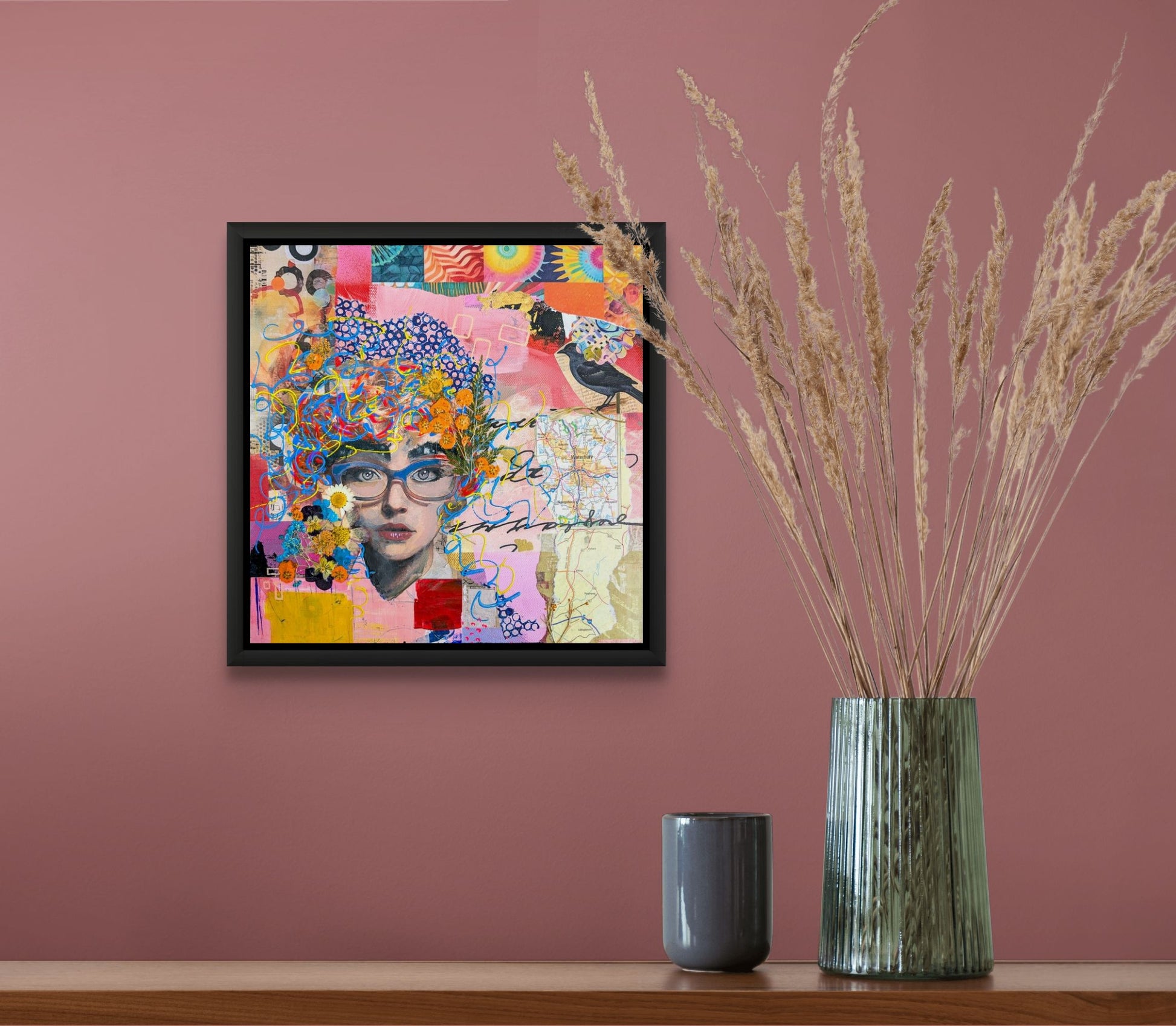 The mixed media work is shown here in a black floating frame (not included) on a wall with a vase and candle on a table below.