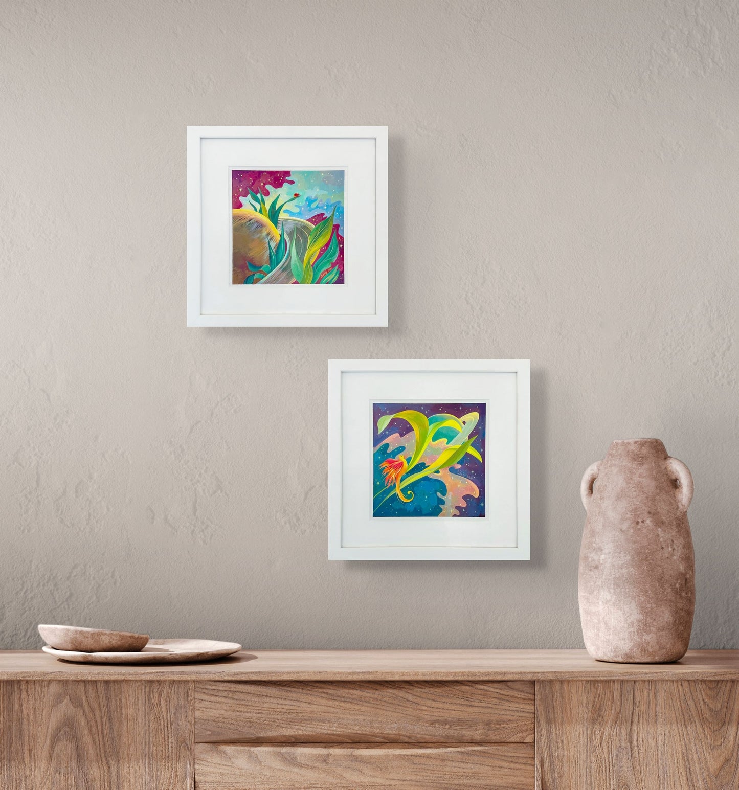 Lady Rings and Saturn Feathers paintings are shown in situ on beige wall over a credenza with clay vase