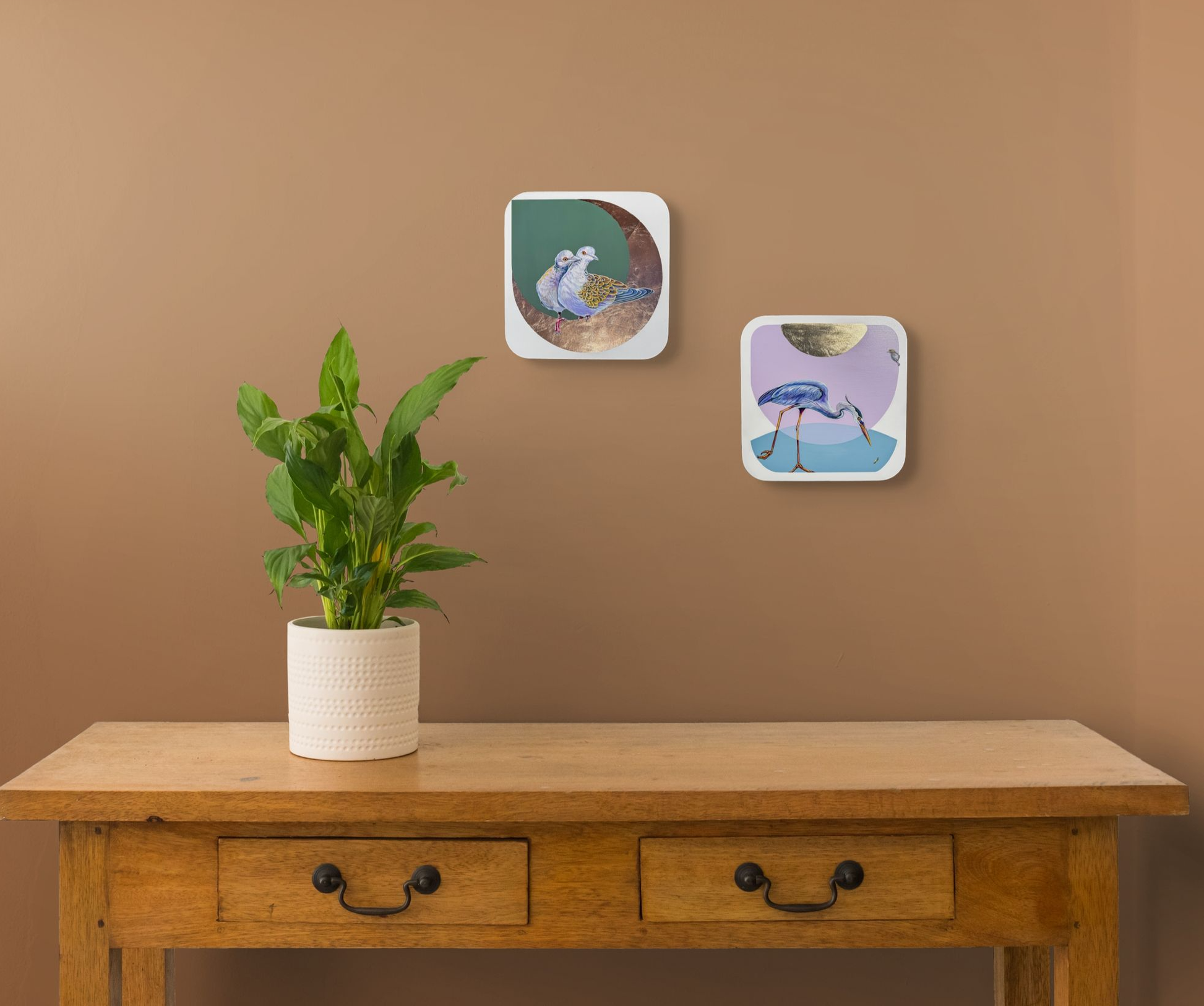 A set of Marie's mini-icons are shown above a wooden side table. Show n are The Honeymooners and Spear Fisher. A plant sits on the table.