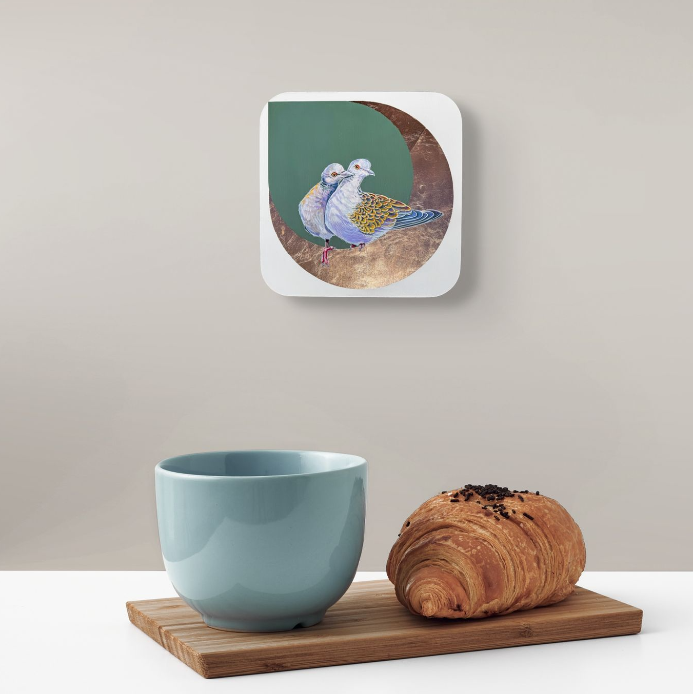 The Honeymooners is positioned on a beige wall over a table where a mug and breakfast croissant sits waiting.