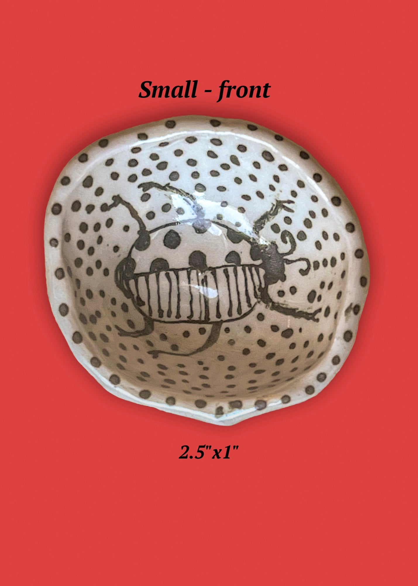Small ceramic bowl with beetle design on a red background. The beetle, in black, is set among polka dots, also black.