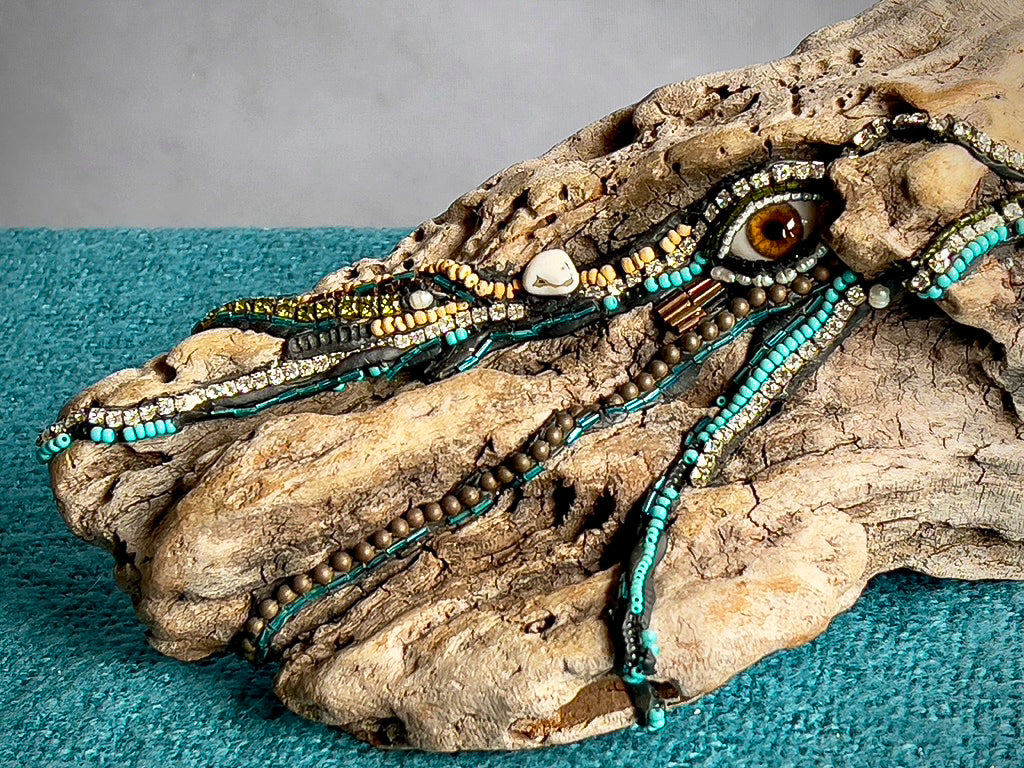 Natural driftwood sculpture decorated with beads, stones, and glass eye by Denise Marshall - close up of detail