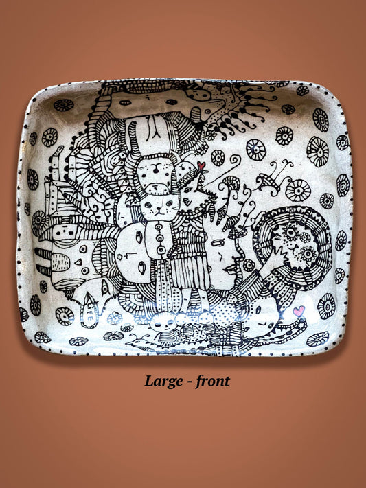 Decorative ceramic plate with black and white patterns on a brown background.There is a wild collection of figures in the center of the plate and a small red heart can be found in the corner.