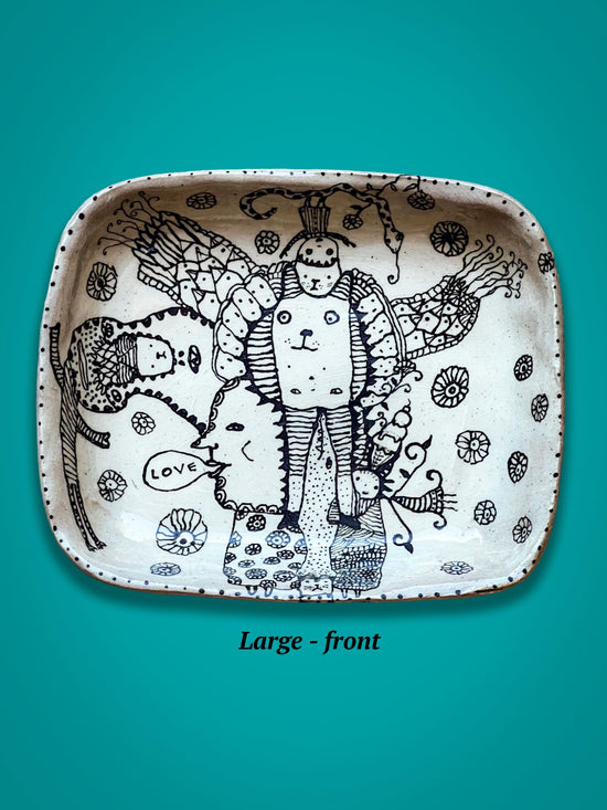 Decorative plate with black line art on a teal background. One of the figures has a speech bubble that says 