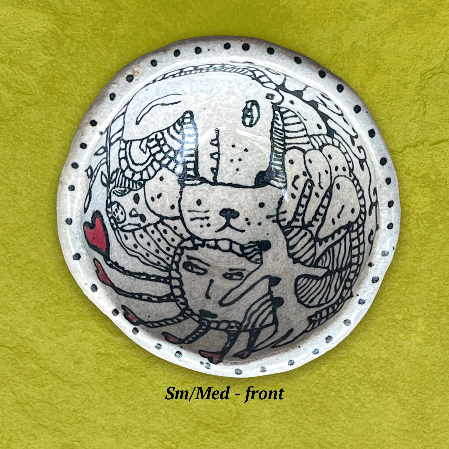 Circular bowl with dog and cat illustrations in black and white. The border of the bowl is decorated with small dots. 