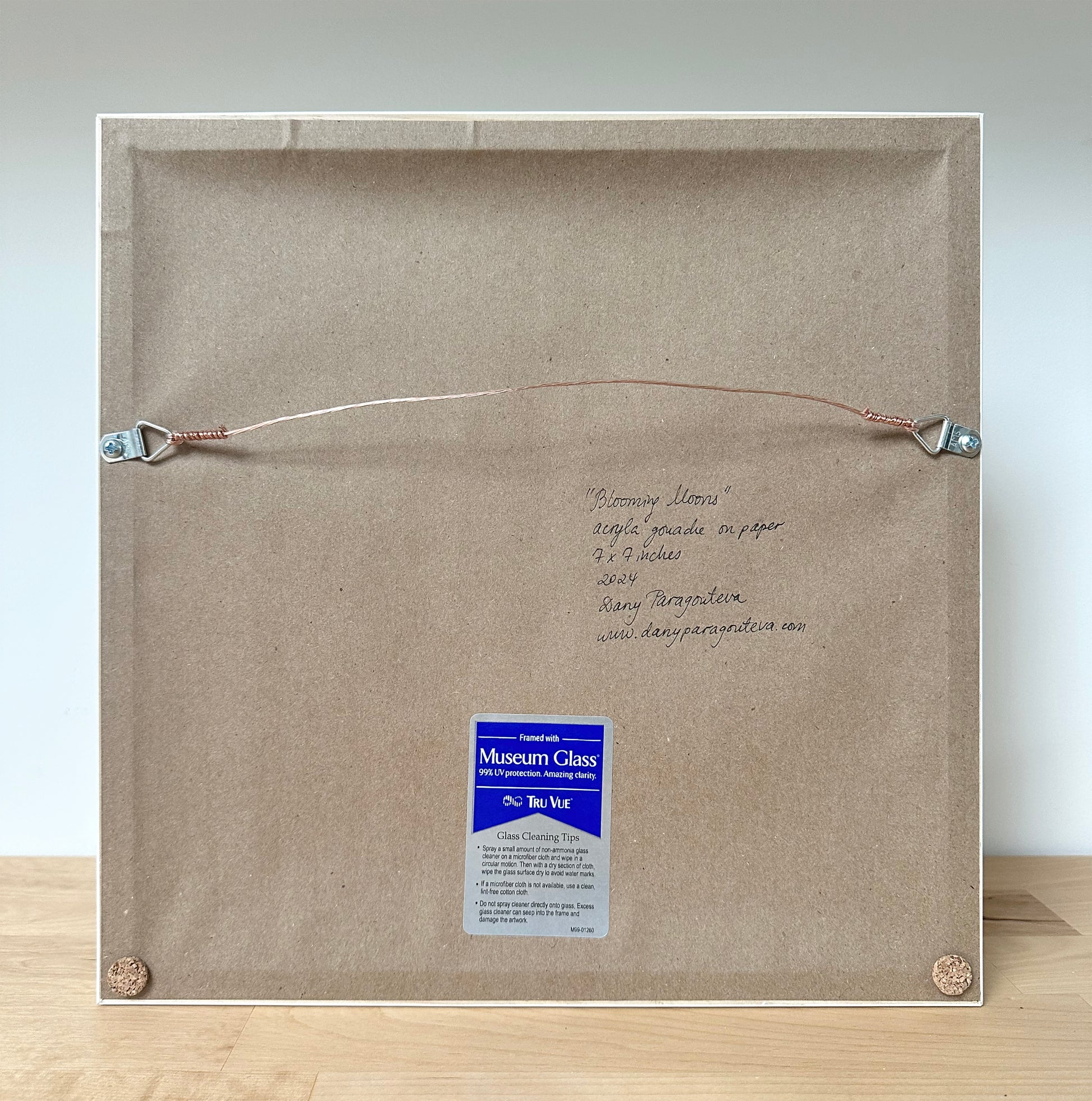 This image shows the framing from the back. It uses museum glass, is professionally framed and has a wire hanger. The artist has signed the back. 
