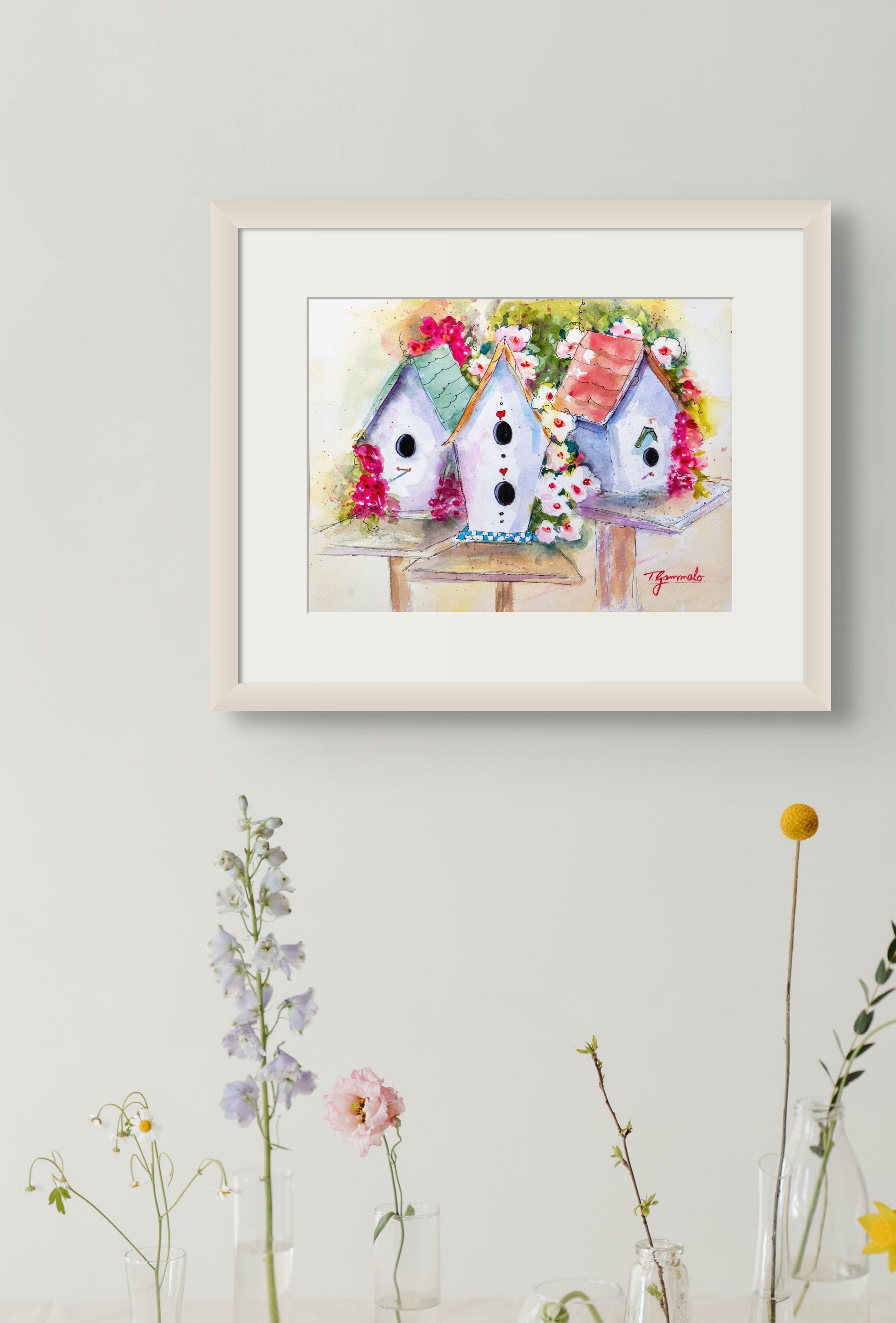 Colorful and whimsical watercolor painting of three birdhouses surrounded by flowers titled 'Cottage Row' by artist Teri Gammalo.  Framed with white mat and white painted wood frame.