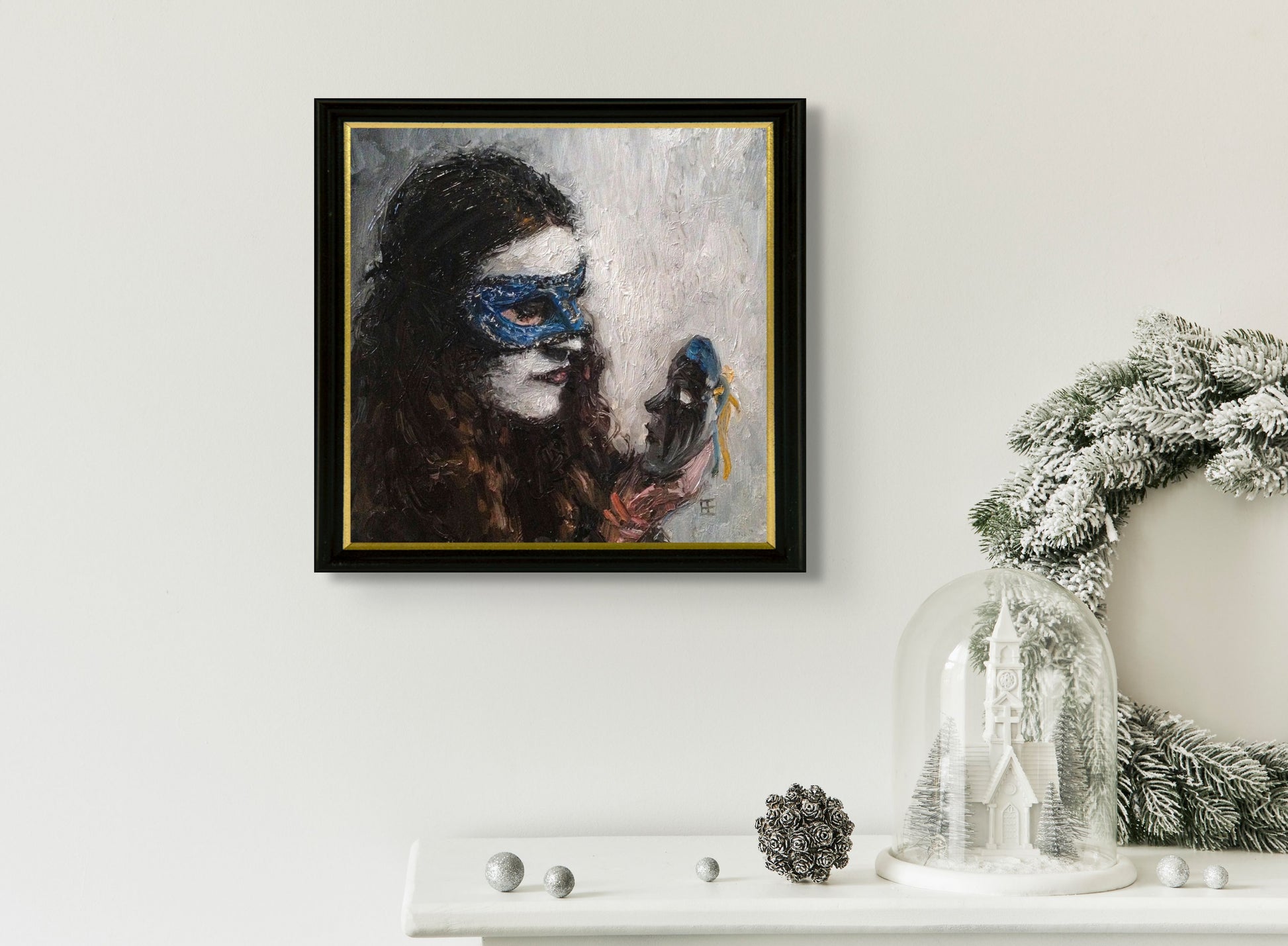 Masked woman with white make up wearing blue mask holds up a new black mask to consider; artist E. E. Jacks; 8"Wx8"H framed and in situ