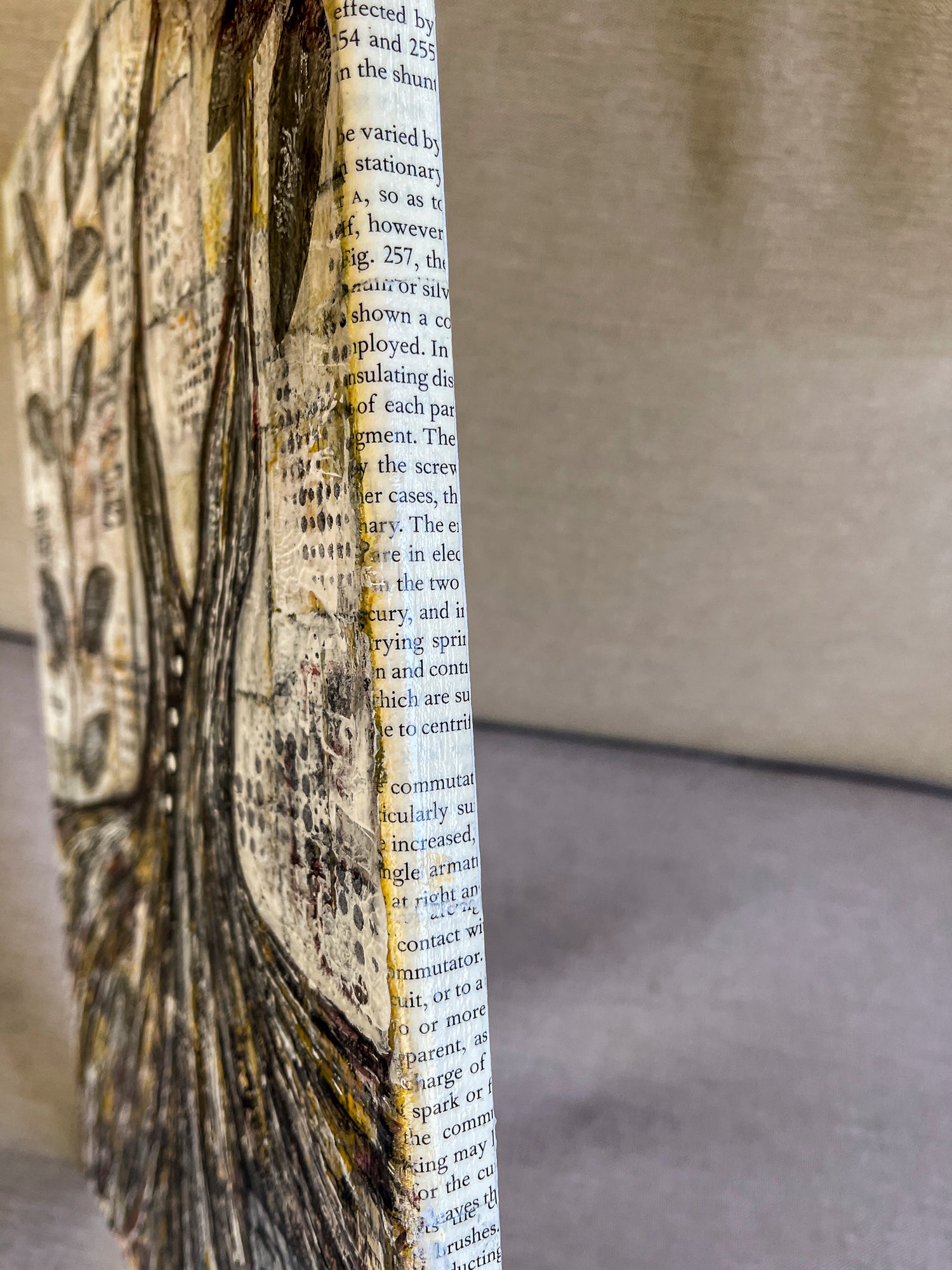 The sides of this unframed piece is covered in book pages. 