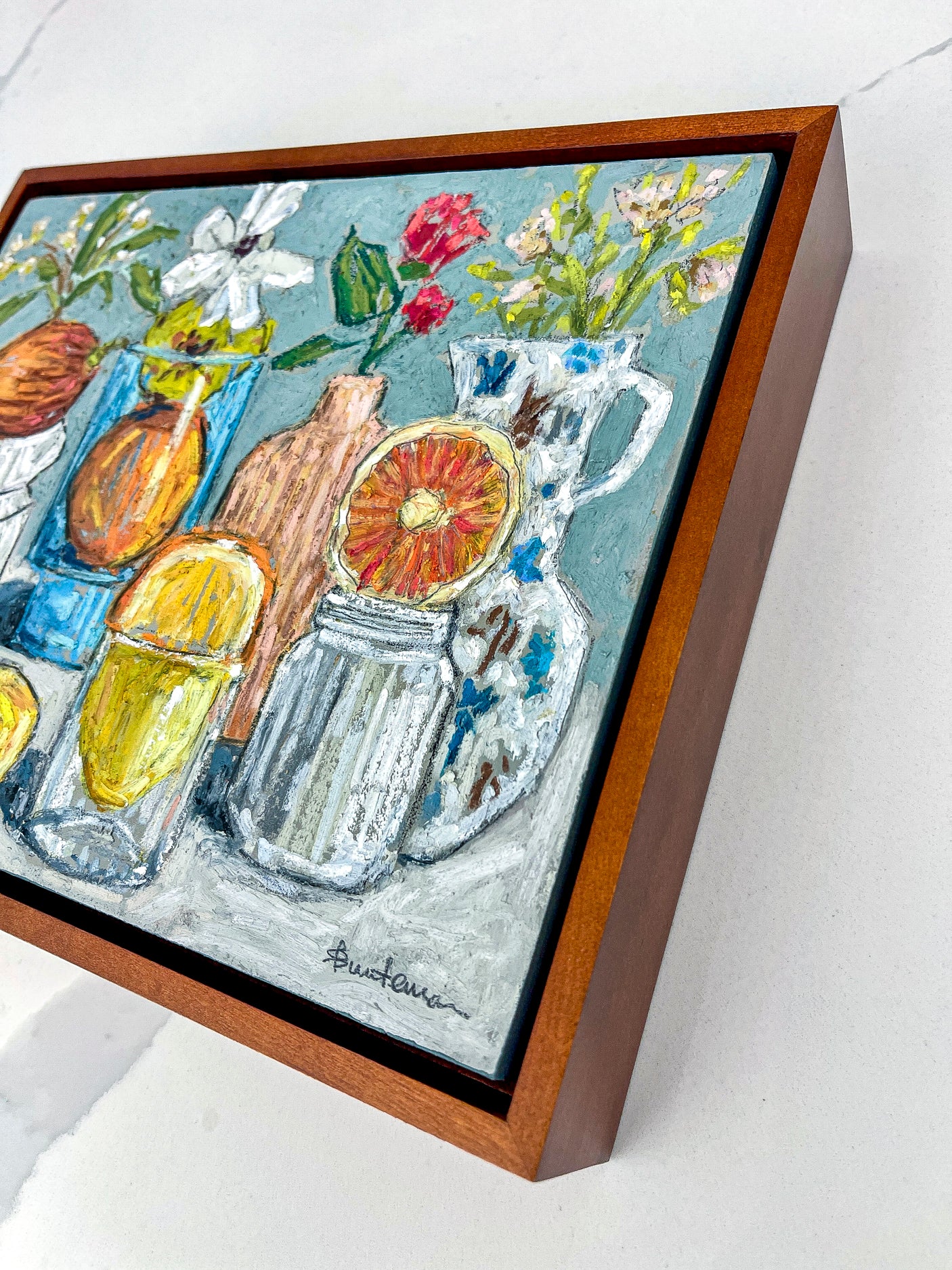 Framed artwork of a still life with lemons, oranges, and flowers on a light blue background. This image shows the wooden cradle frame.