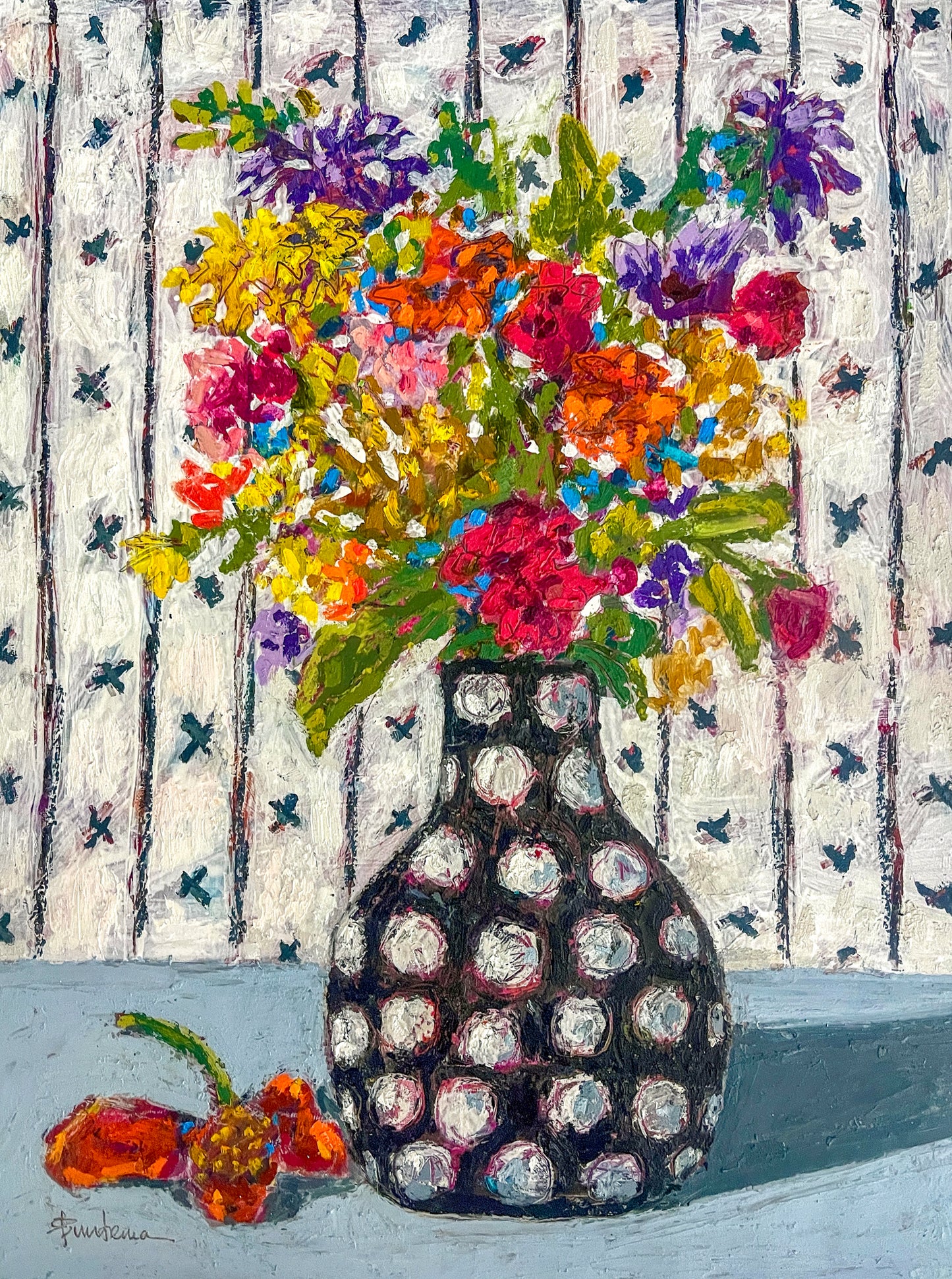 Pattern and color are the hallmarks of this floral still life painting. A black and white polka dot vase, sits on a table against a patterned wallpapered background. The bouquet looks to be a bunch of wildflowers, with a lone flower that has dropped and lays on the table.  