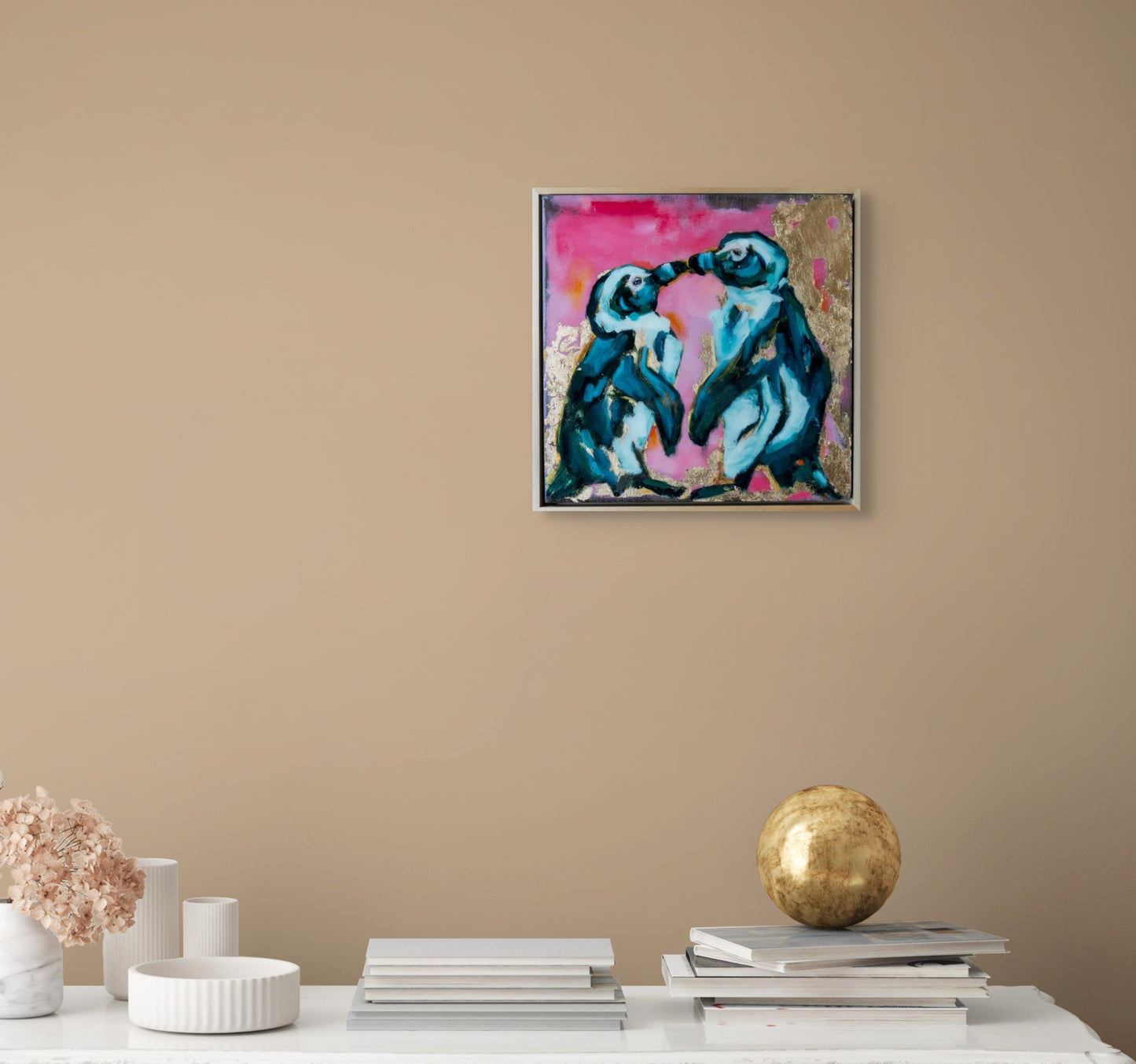 12.5"x12.5" painting of two Penguins is mixed media; using acrylic and oil, pencil, and gold leaf with glossy resin finish on surface; blues, pinks, and gold; artist Shaney Watters; has raw maple float frame; in situ