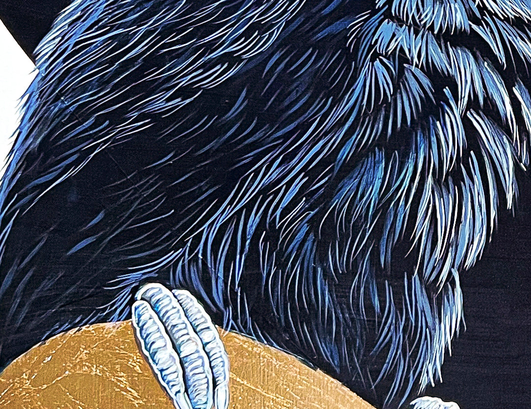 This close up images shows the detail of the blues and gray feathers and the toucan's claws resting on the gold shape.