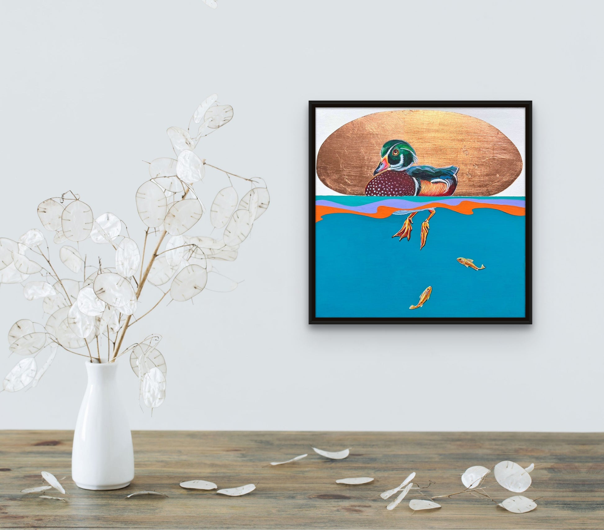 Framed colorful mallard duck with copper leaf background and underwater view of his dangling feet and two small fish in situ; artist Marie Lavallee; 12"x12"