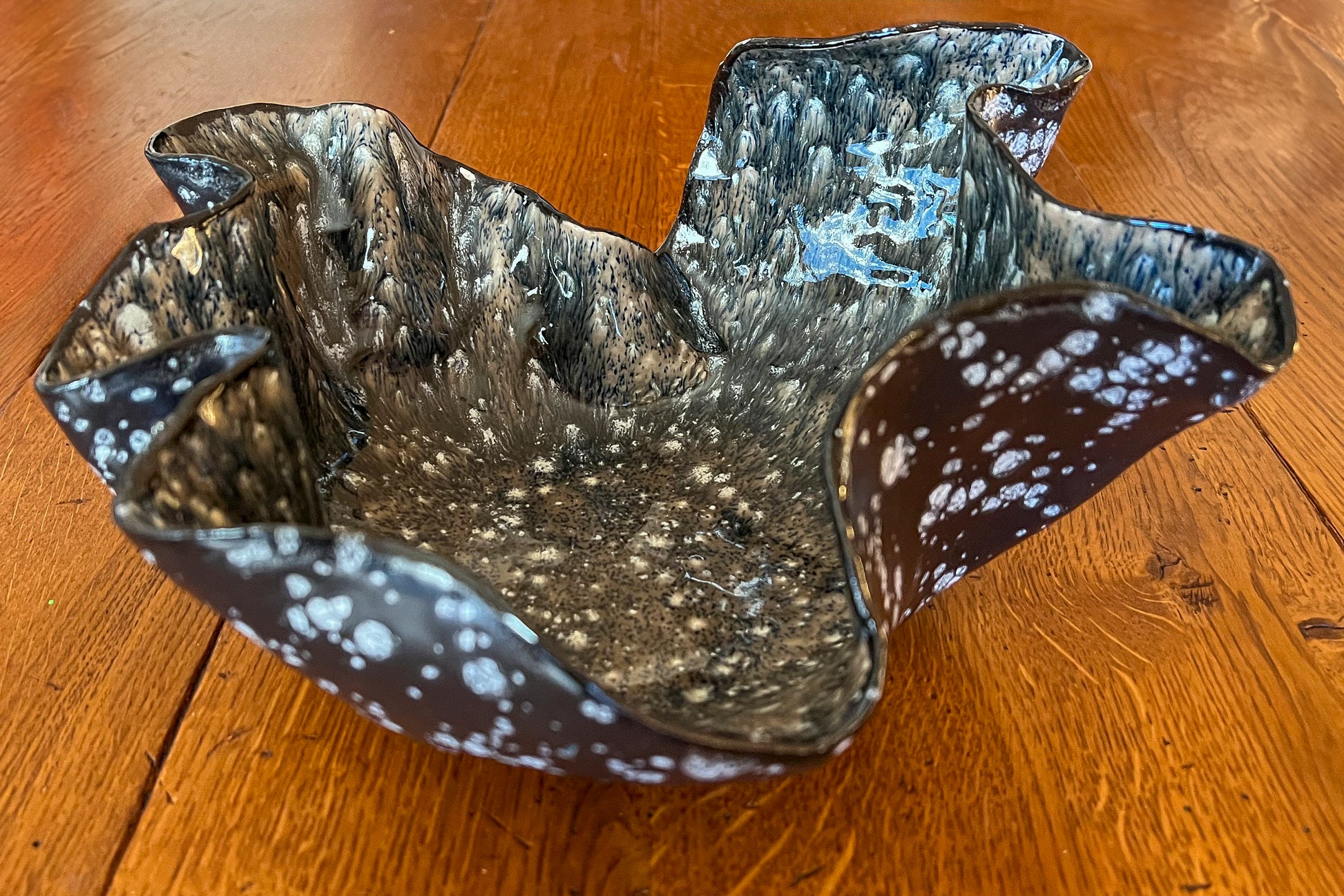 Free form black ceramic bowl with white crystal glazing on the interior of the bowl and black and white speckled glaze on the outside