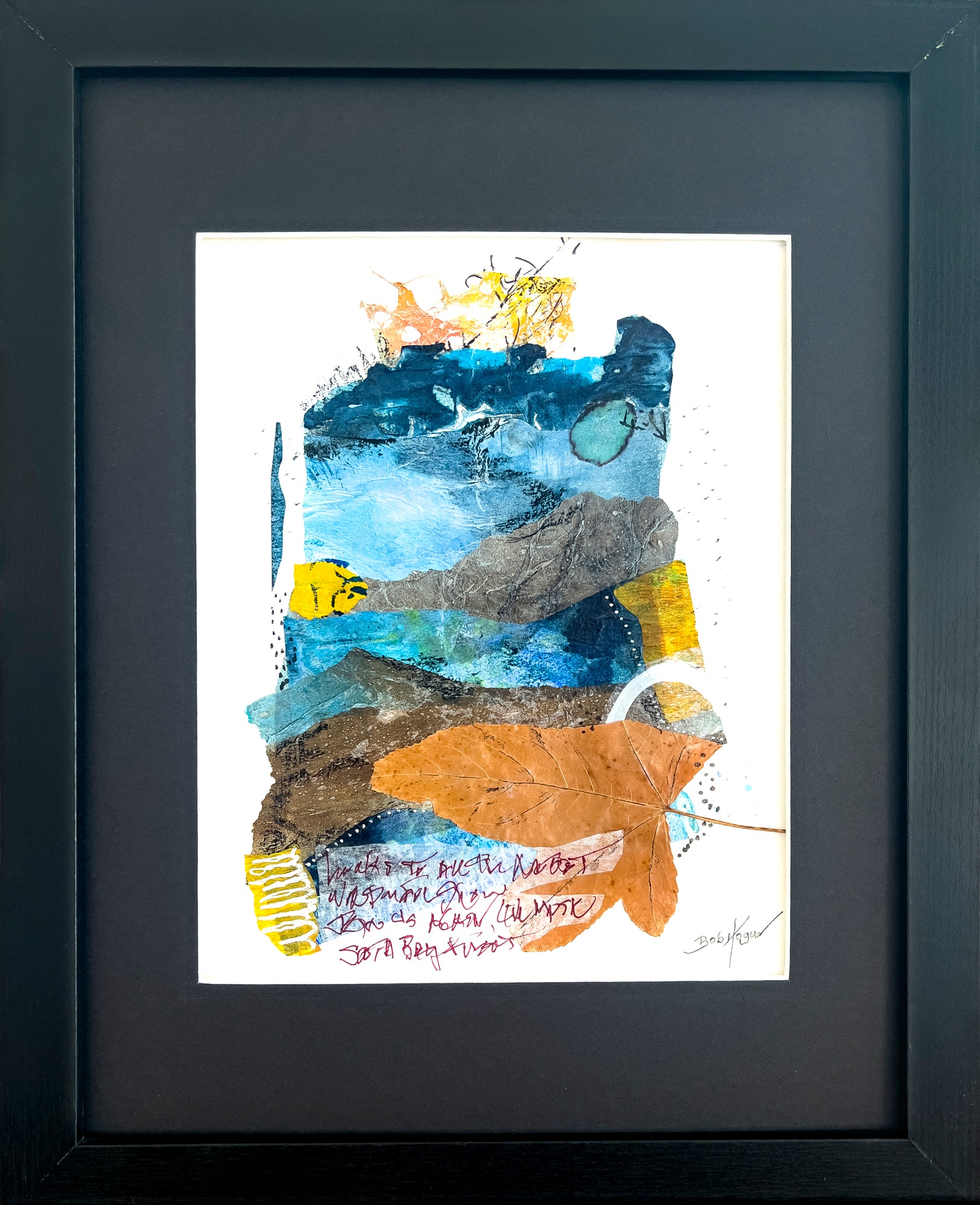 A collage set against white watercolor paper with a dried leaf as its center focus. Other elements included pieces of paper in natural blue and yellow hues, ink markings and a few lines of indistinguishable writing; artist Bob Hogue;  shows painting framed in a black wooden frame and black mat.