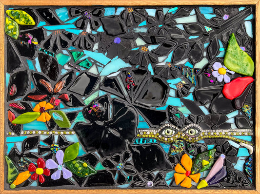 Glass mosaic artwork of leaves and flowers using fused glass of black interspersed with bright colors; image contains a set of glass eyes surrounded by rhinestones; artist Denise Marshall