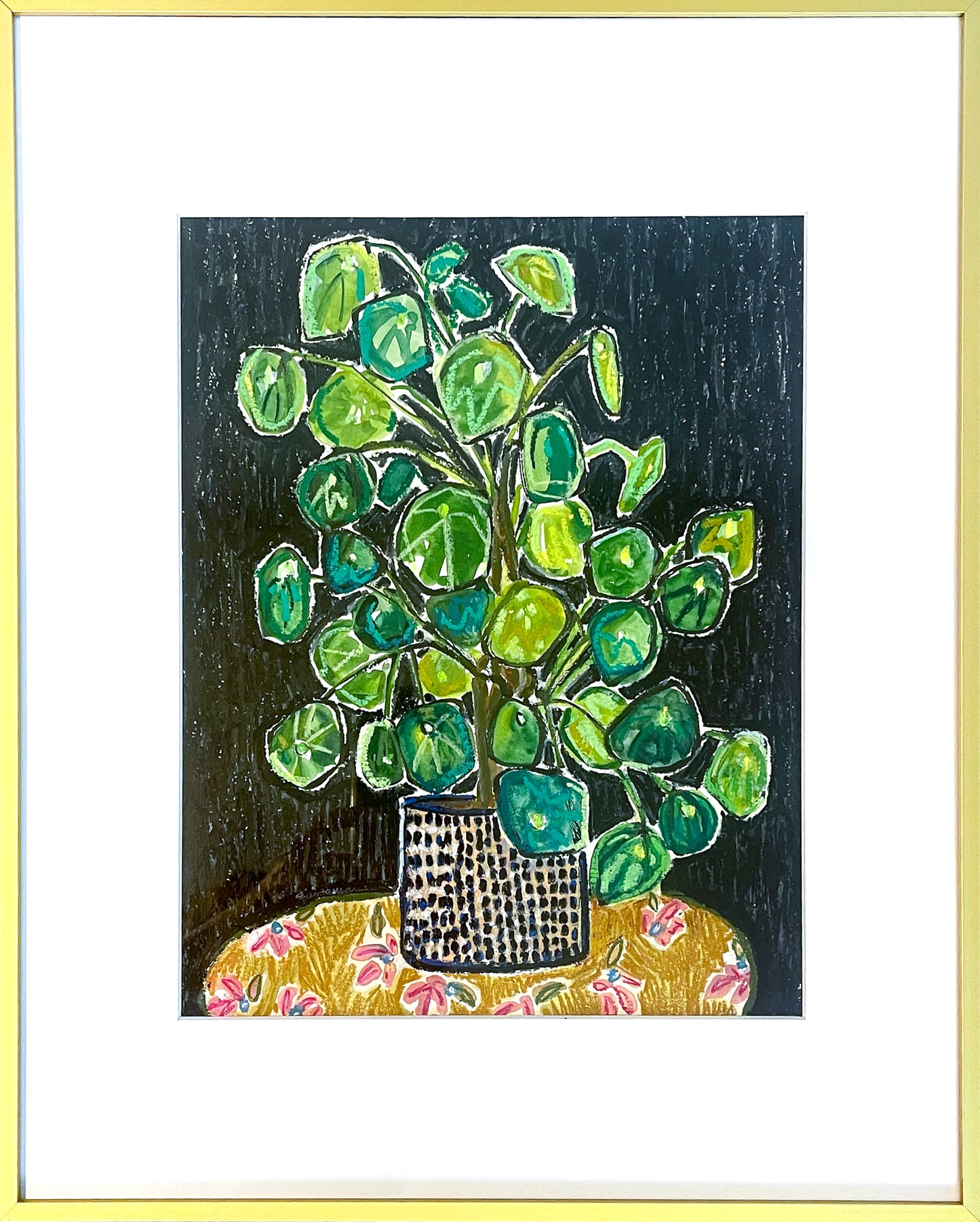 Colorful still life of green pilau plant sitting on yellow fabric with red floral images; black background; watercolor and oil pastel, 17"x23" framed; artist Rachel Bunteman