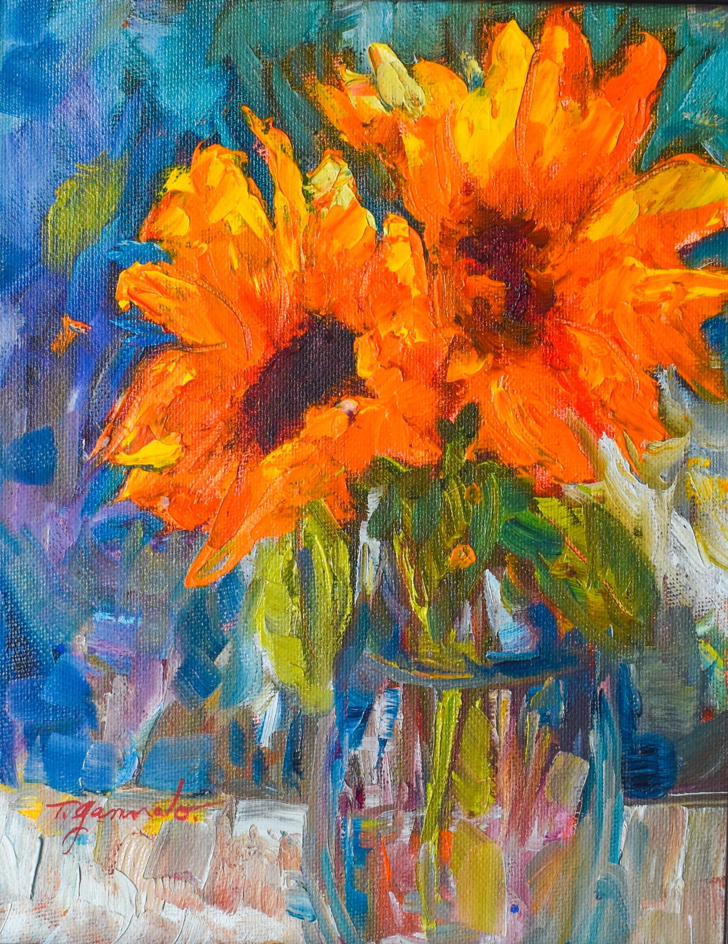 Two sunflowers are positioned in a clear vase. The background is teal and blue hues. 