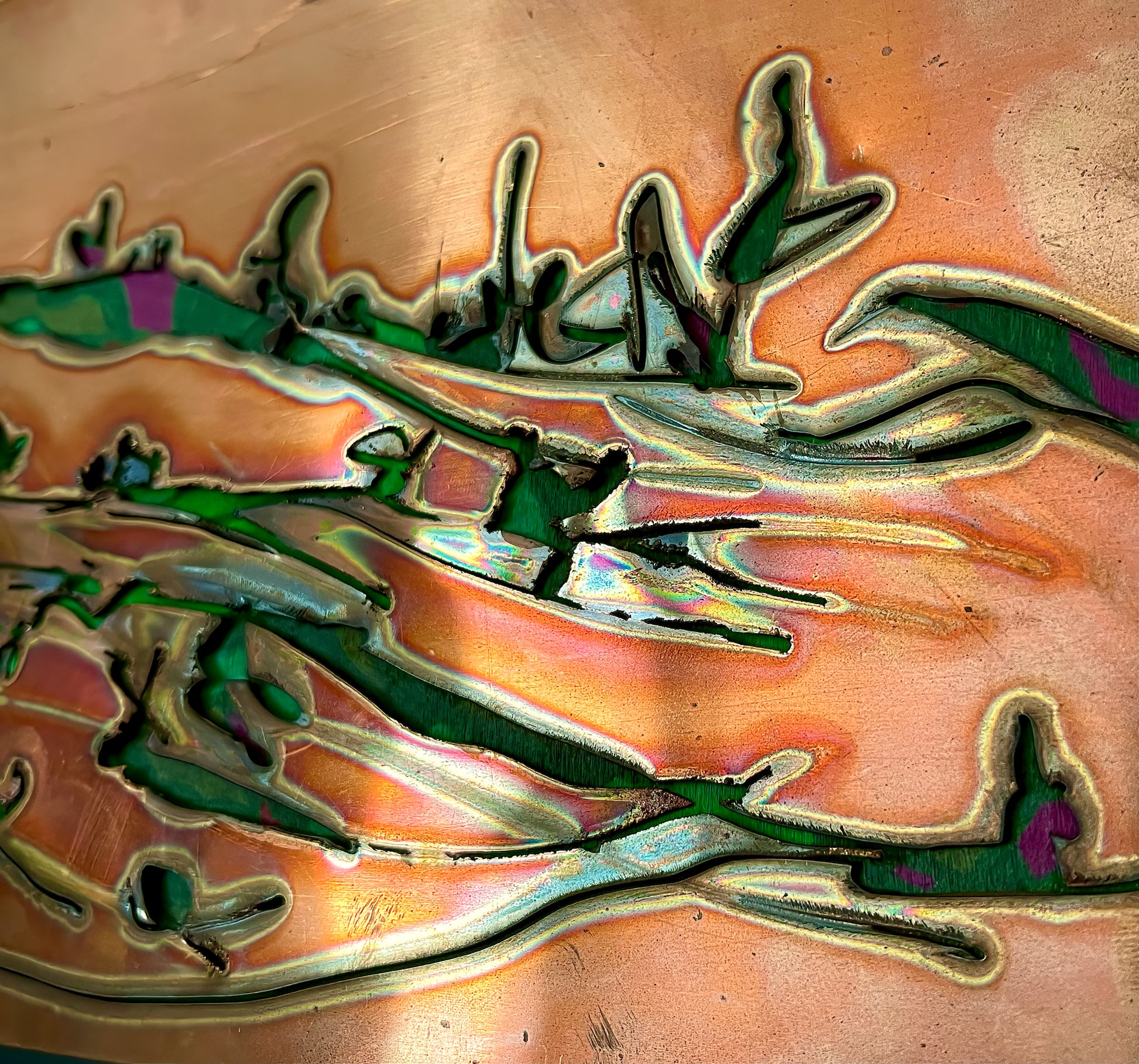 A close up image of a portion of swept away shows the strokes of the dark green acrylic on the copper background. There are variations of greens and spots purple.